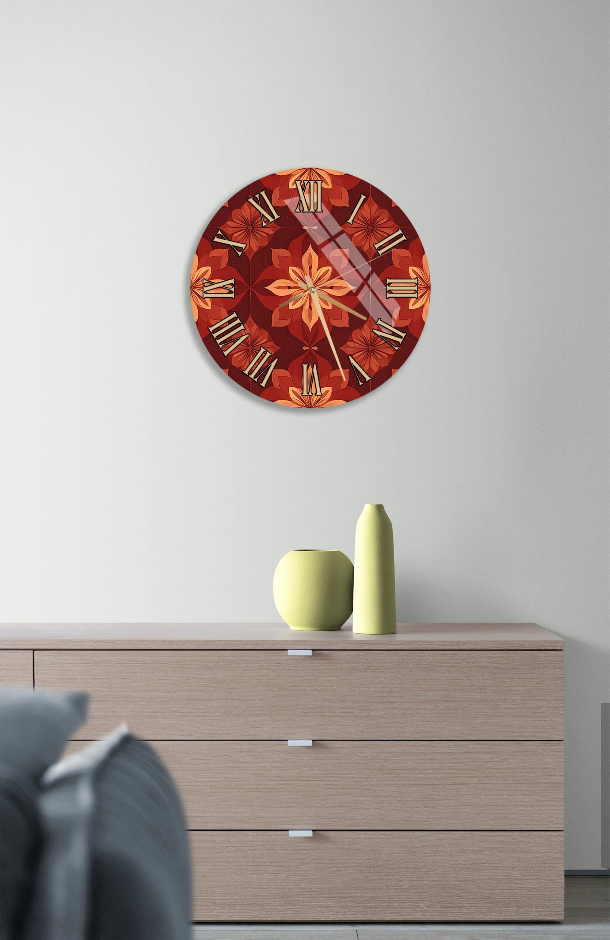 a wall clock with a floral design, mounted on a wall above a wooden dresser. The dresser has a vase and a small figurine on top of it.