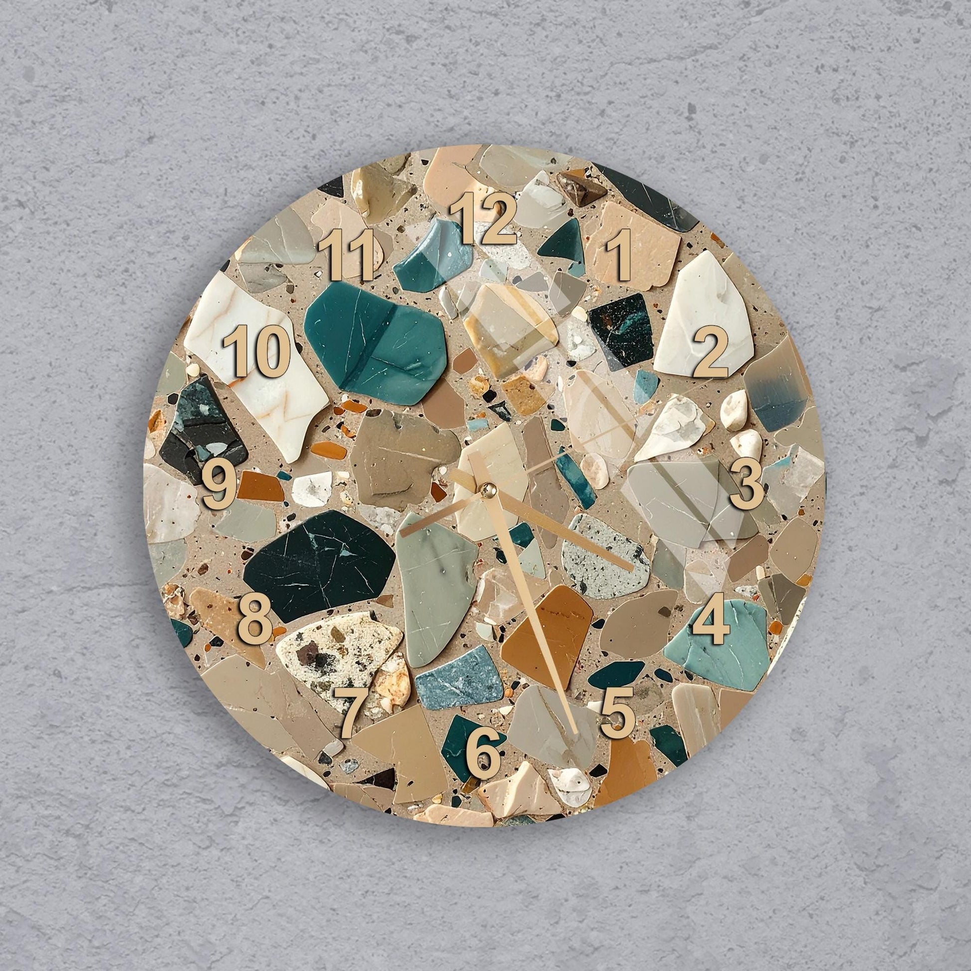 A round wall clock with a mosaic design made up of various colored tiles, including shades of green, brown, and beige.