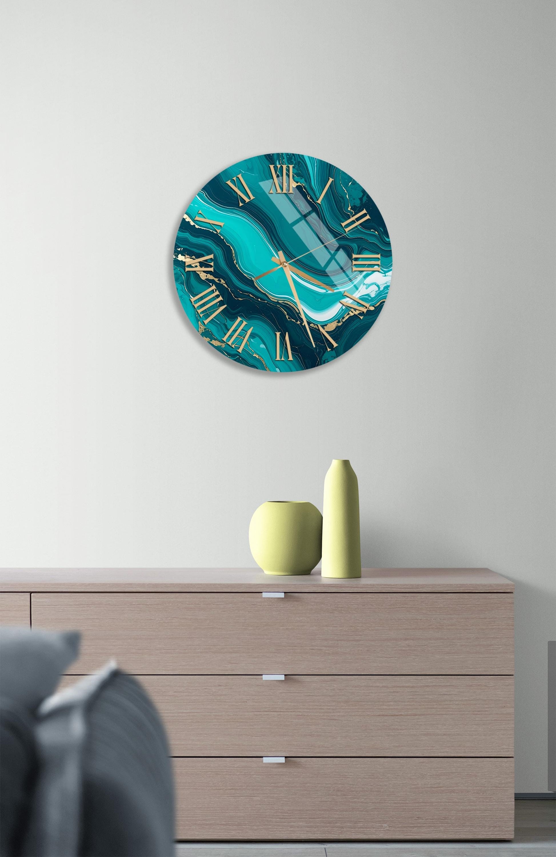 a modern living room with a large turquoise marble-style clock hanging on the wall above a wooden dresser. The dresser has three drawers and a small yellow vase on top.