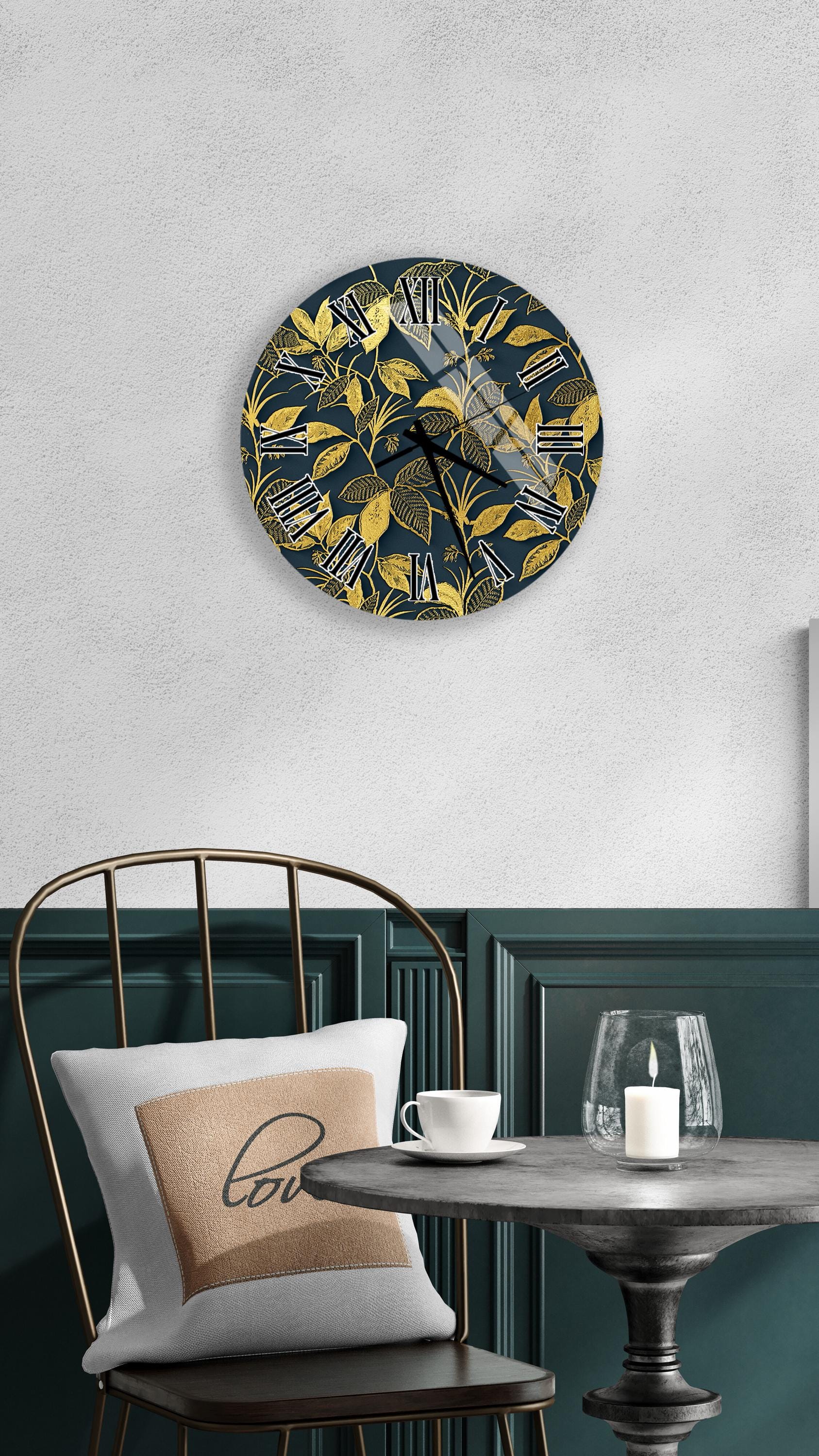 a modern interior design with a round wall clock featuring a gold leaf pattern, a white table with a candle and a cup, and a black metal chair with a white pillow.