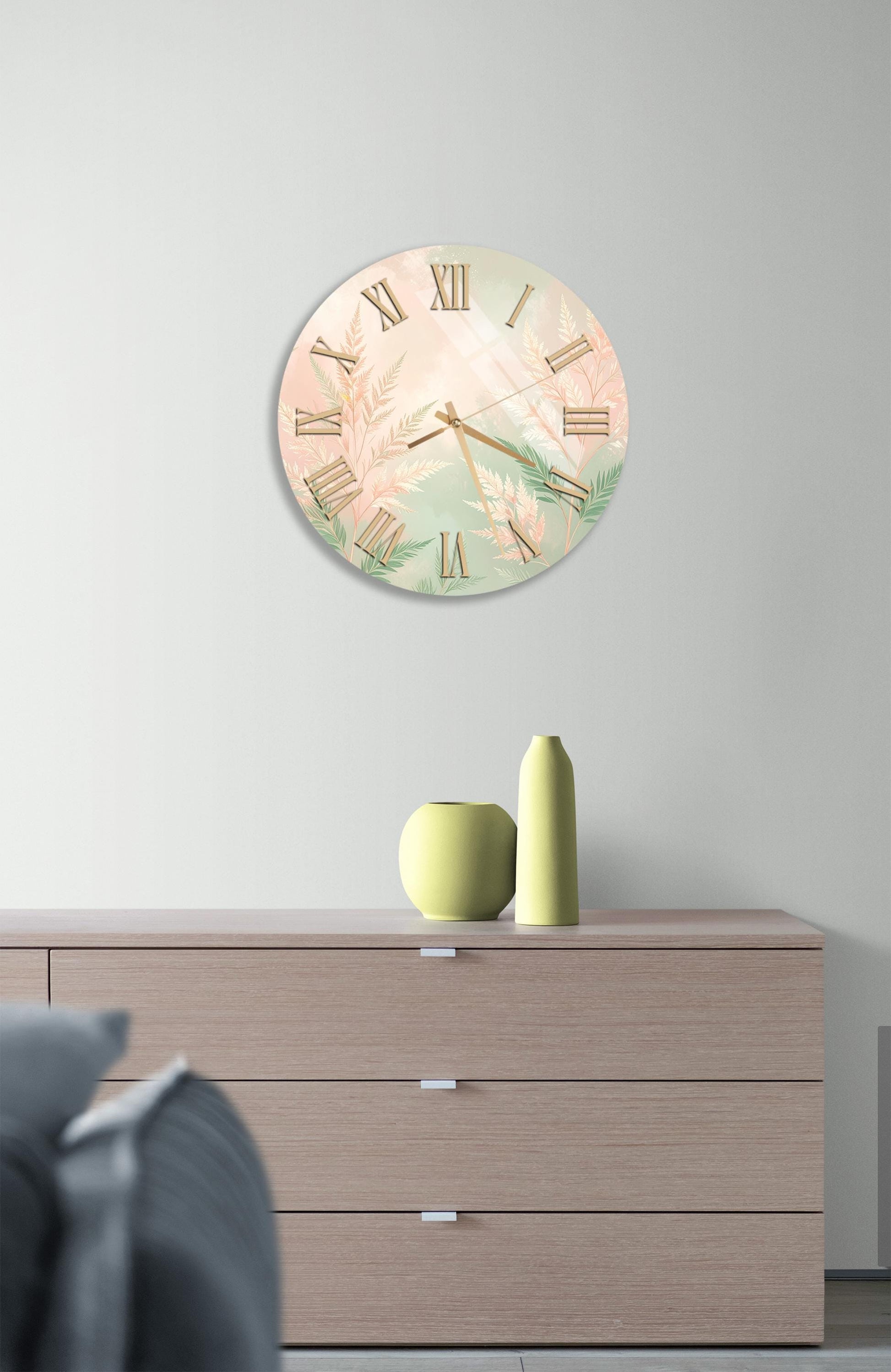 a wall clock with a floral design, mounted on a wall above a wooden dresser with three drawers.