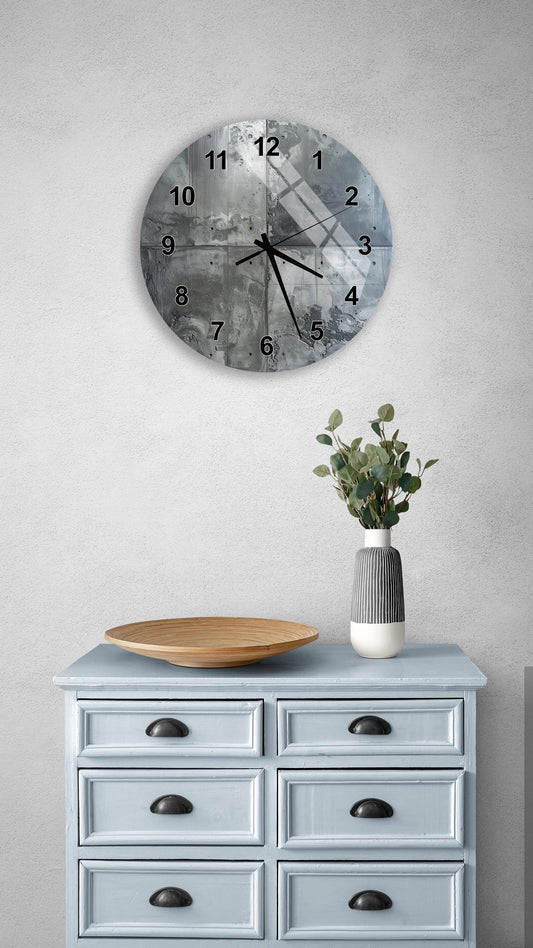 a wall clock with a black and white design, mounted on a wall above a light blue wooden dresser with six drawers. The dresser also has a vase with greenery on it, and a wooden plate on top.
