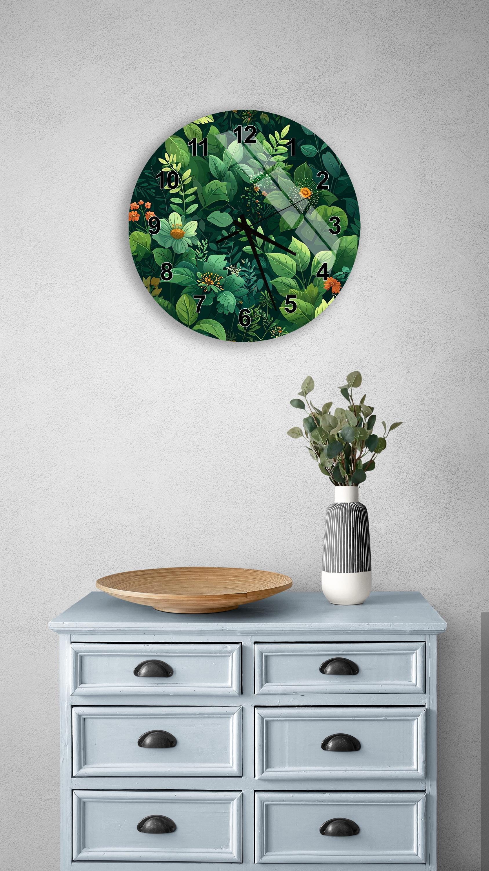 a wall clock with a green leafy design, a wooden bowl, and a vase of greenery on a light blue dresser.