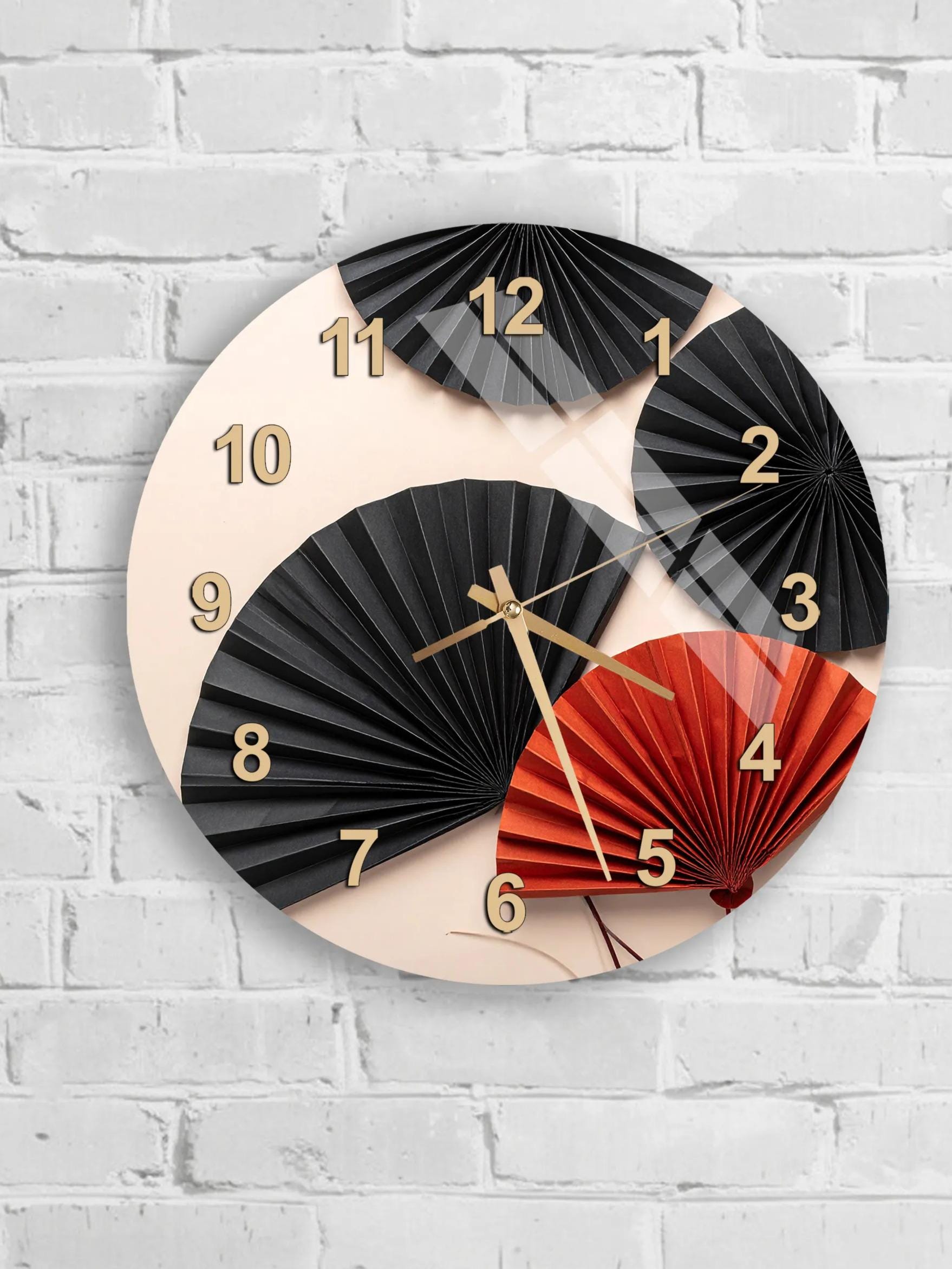 A wall clock with a design featuring black and red fans against a white brick wall.