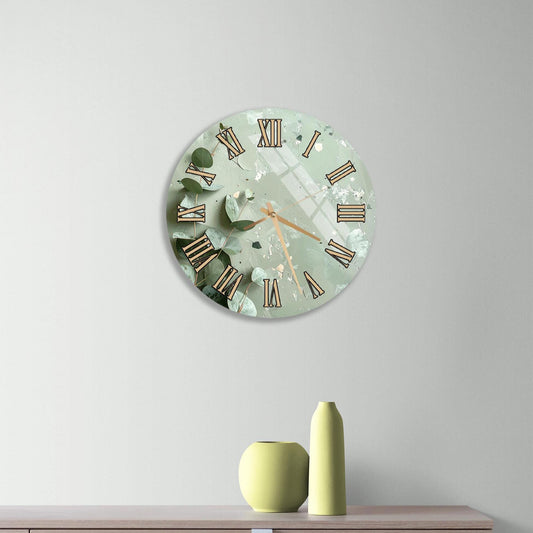a wall clock with a green and gold design, mounted on a wall above a wooden dresser with three drawers.