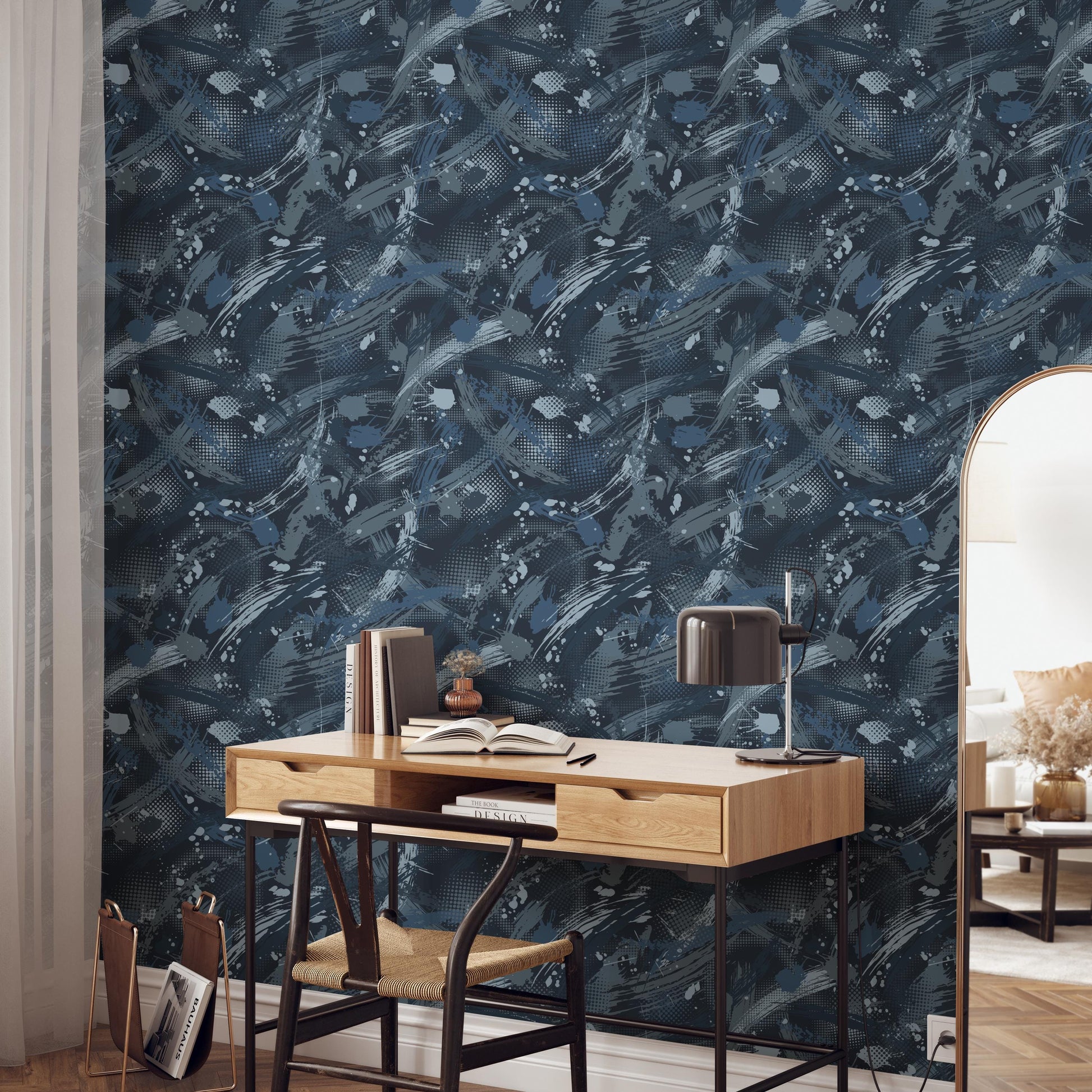 a modern workspace with a wooden desk, a black lamp, and a bookshelf. The wall behind the desk has a blue and white abstract pattern, creating a visually striking backdrop for the workspace.