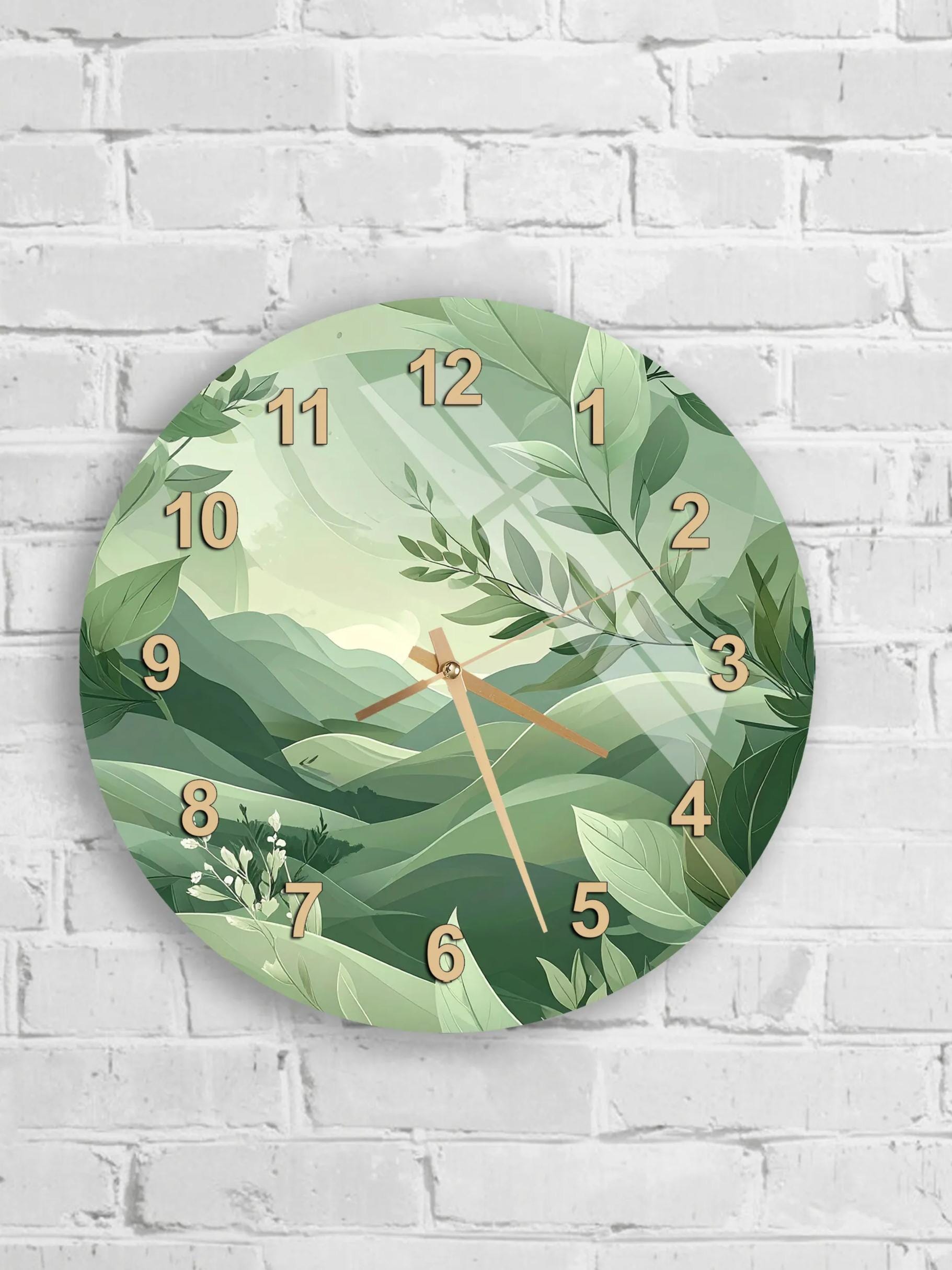 A round wall clock with a green leafy background and a landscape scene.