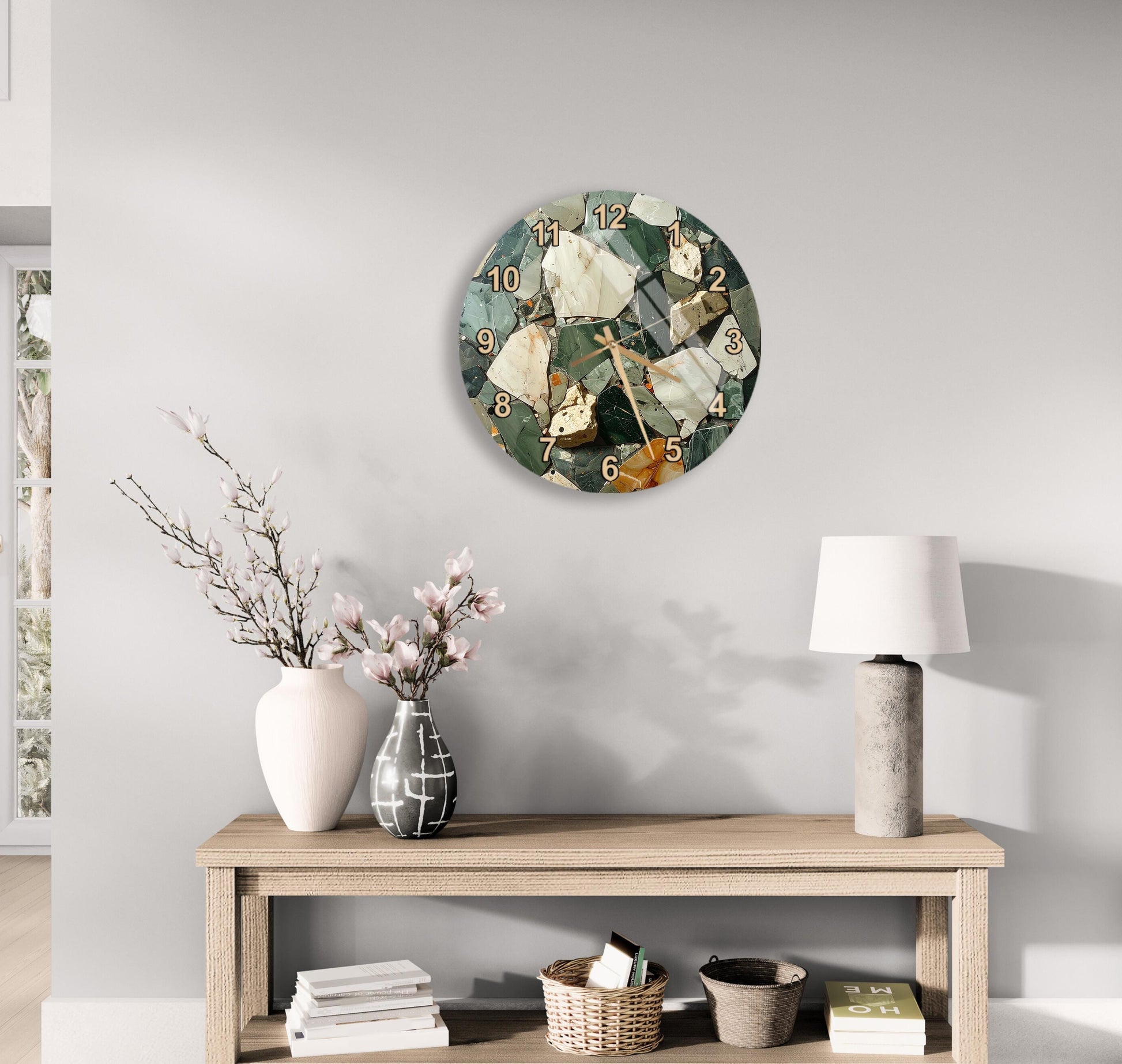 a modern living room with a wooden console table, a round wall clock with a mosaic design, a vase with pink flowers, and a lamp on the table.