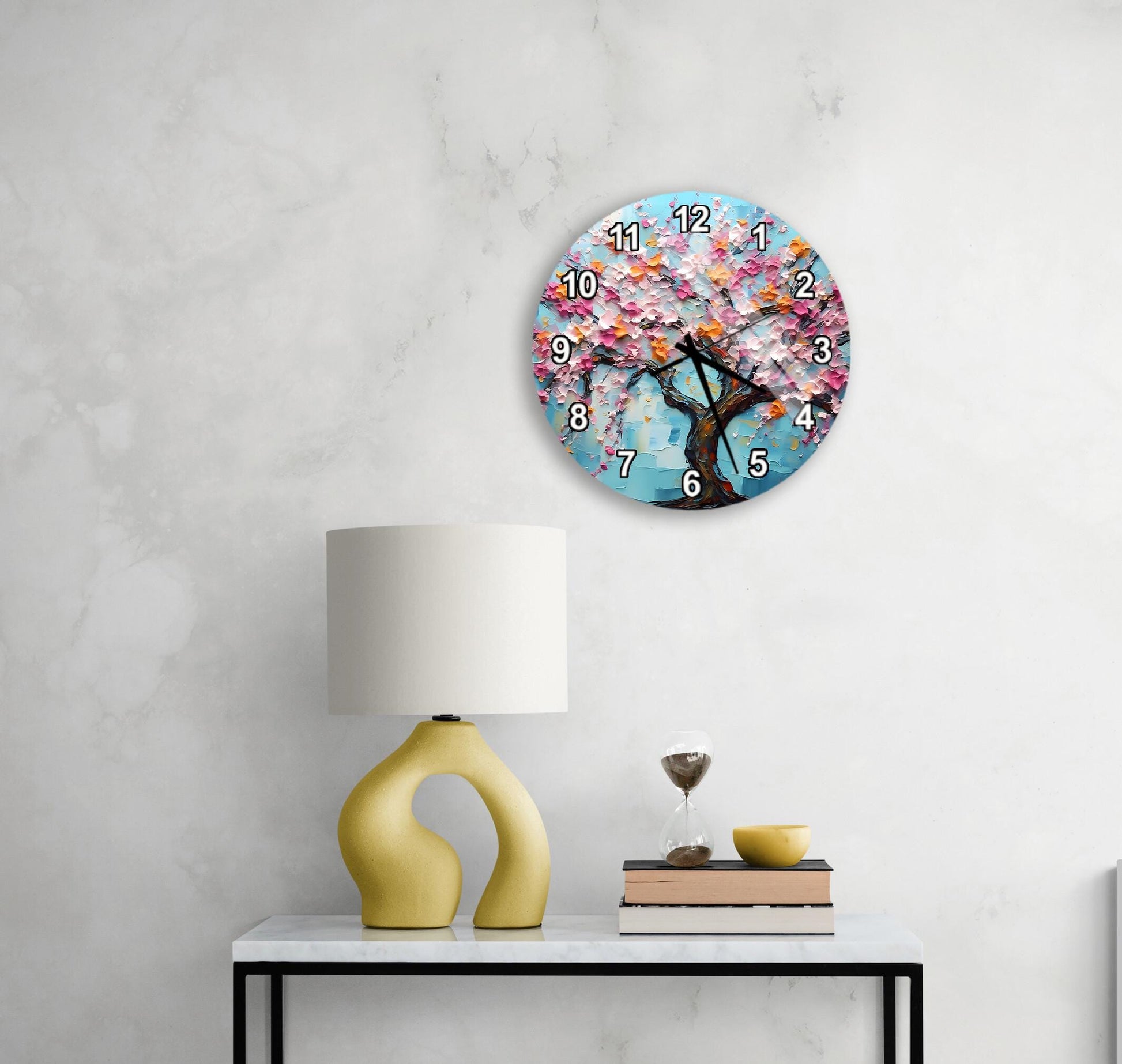 a round wall clock with a tree design, a yellow lamp on a table, and a stack of books.