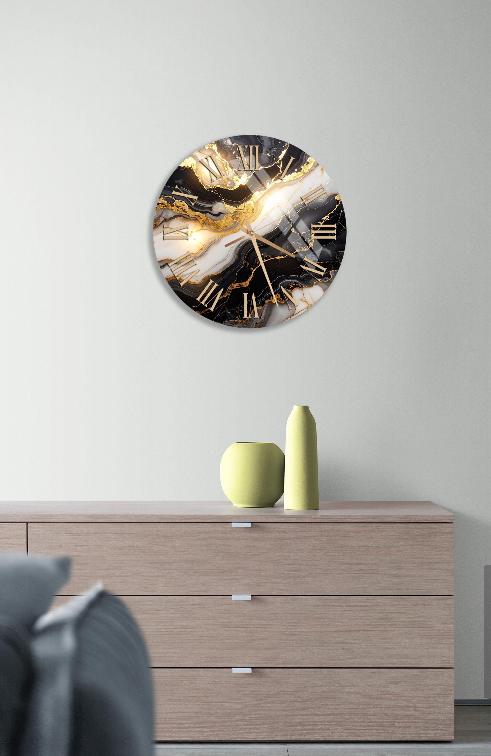 a modern clock with a black and white marble design, mounted on a wall above a wooden dresser.
