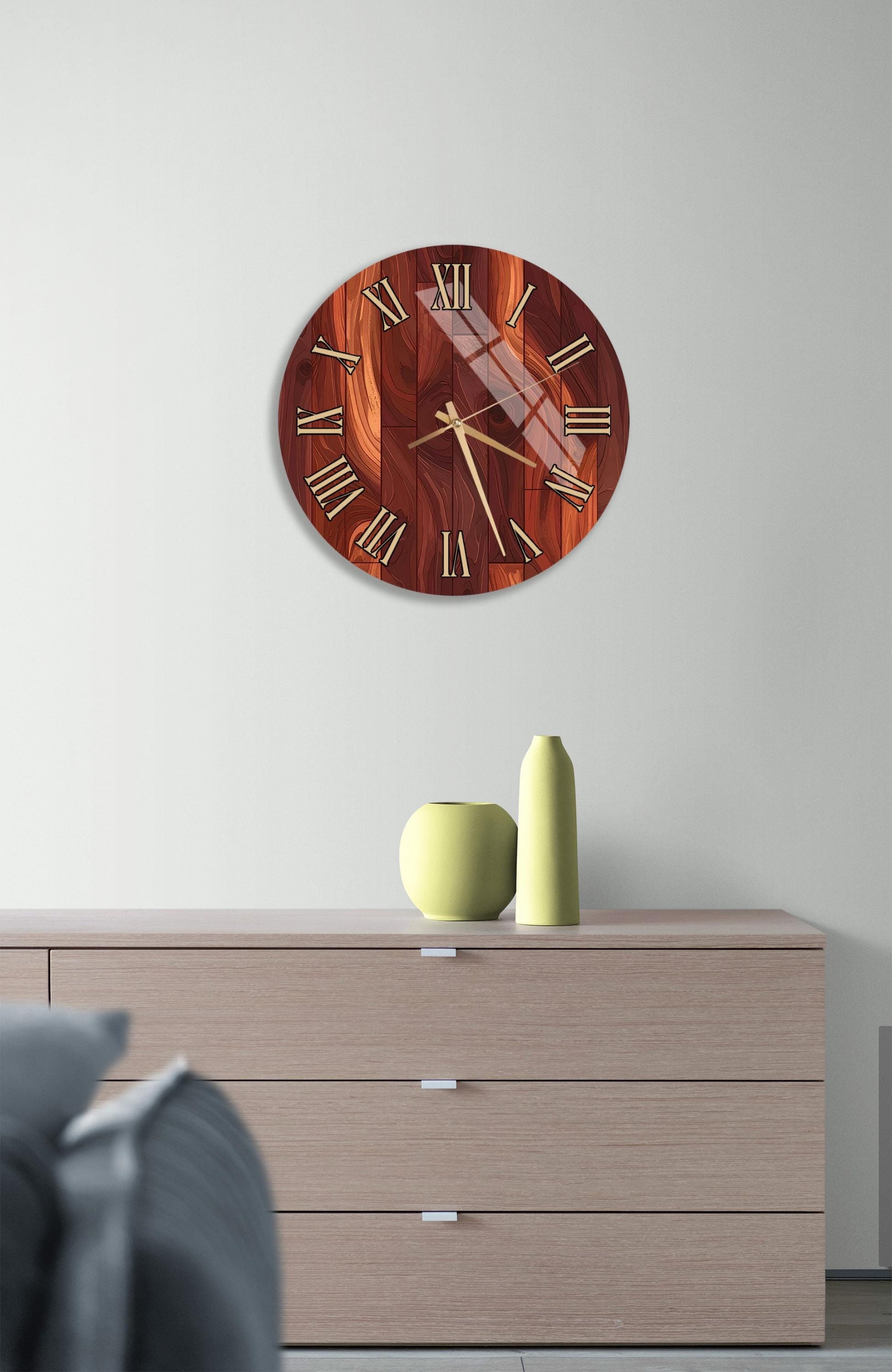 a wooden clock with a dark brown finish, mounted on a white wall above a wooden dresser with three drawers. The dresser also has a small green vase and a yellow vase on it.