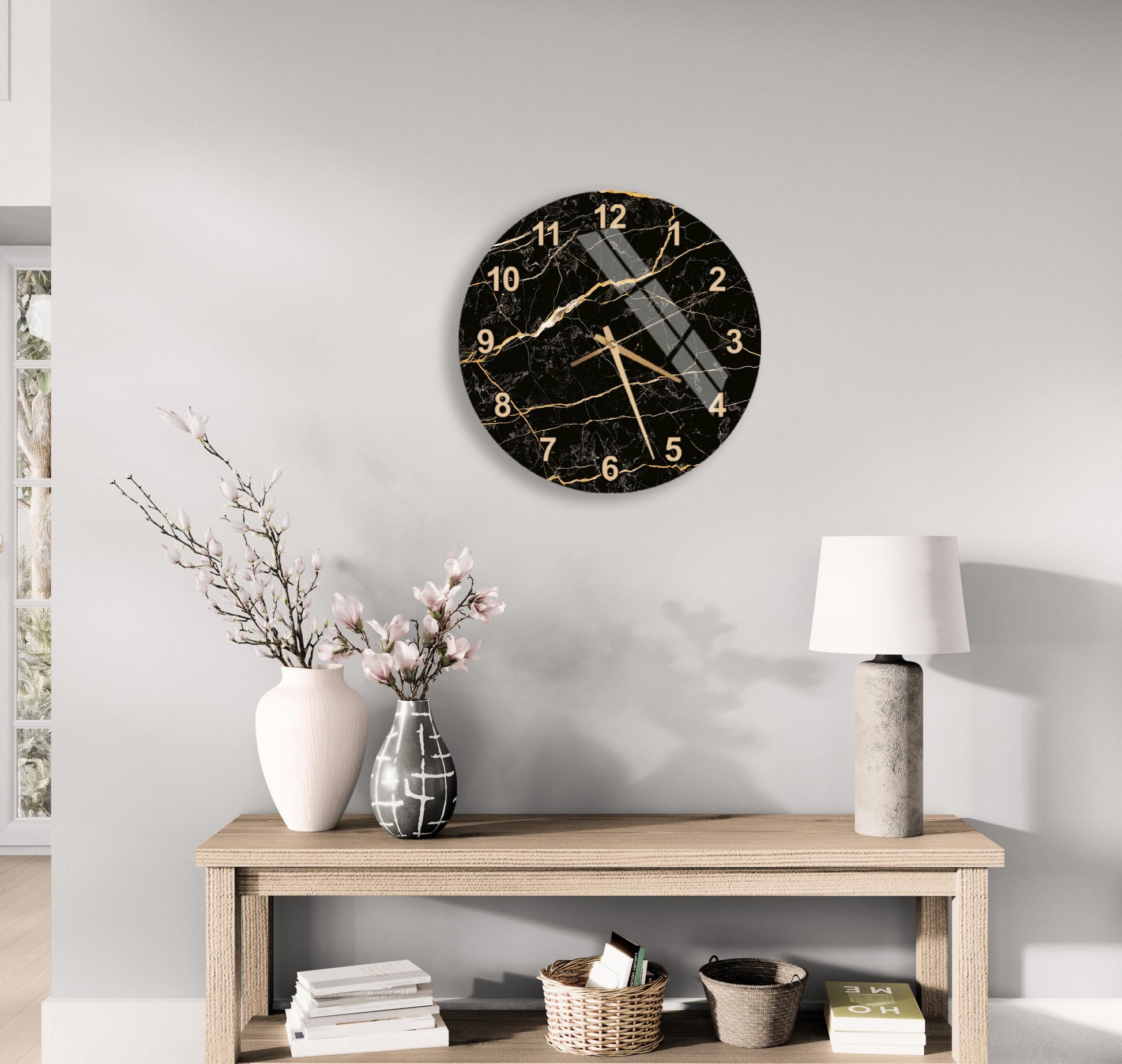 a modern living room with a wooden console table, a round black and gold wall clock, a white vase with pink flowers, and a white lamp.