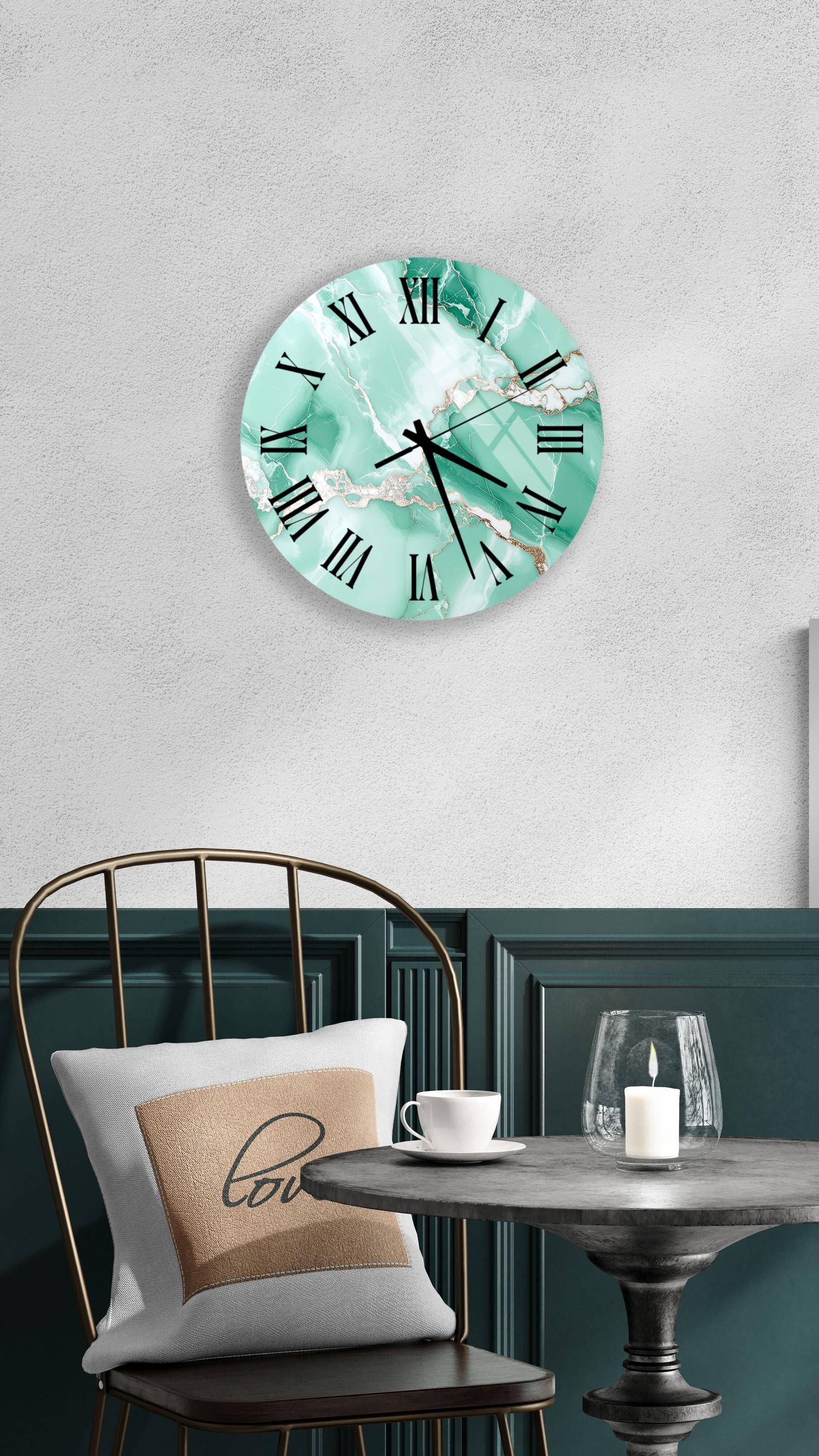 a wall clock with a marble-like design, a white table with a candle and a cup, and a chair with a pillow.