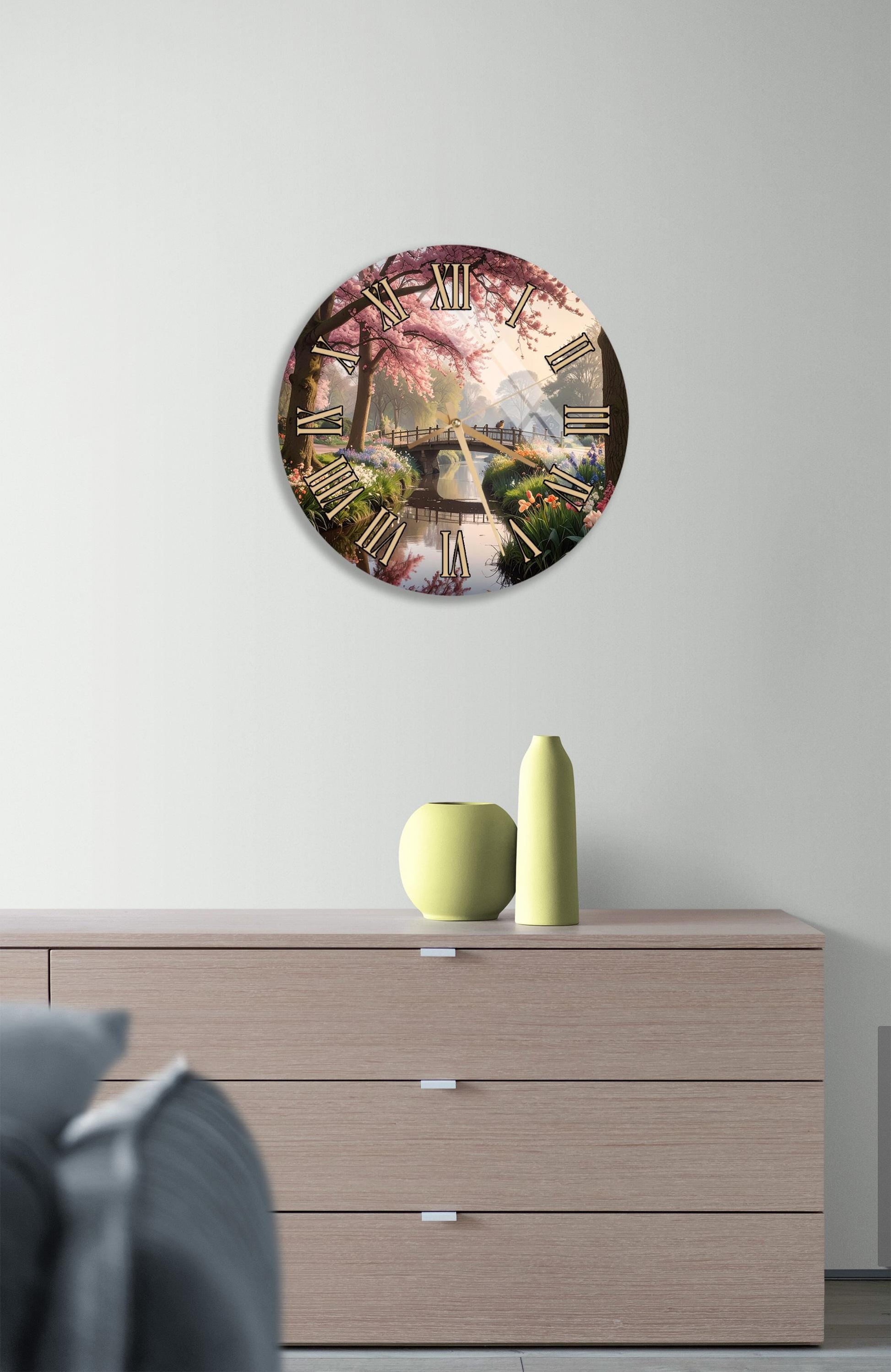 a clock with a floral design on the face, mounted on a wall above a wooden dresser.