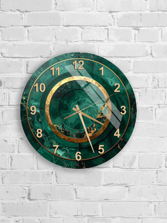 A wall clock with a green marble-like design and gold accents, mounted on a white brick wall.