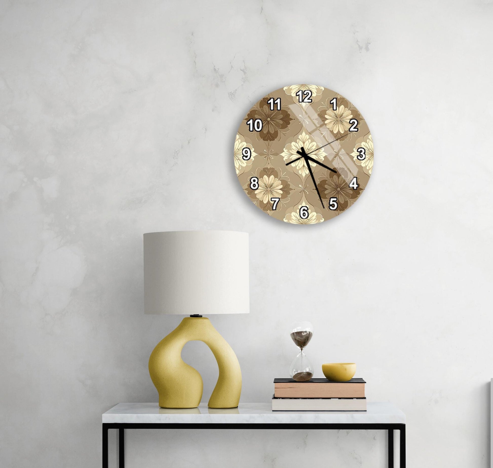 a modern living room with a white marble wall, a round clock with a floral design, a yellow lamp with a unique curved base, and a small table with a book and a glass of wine.