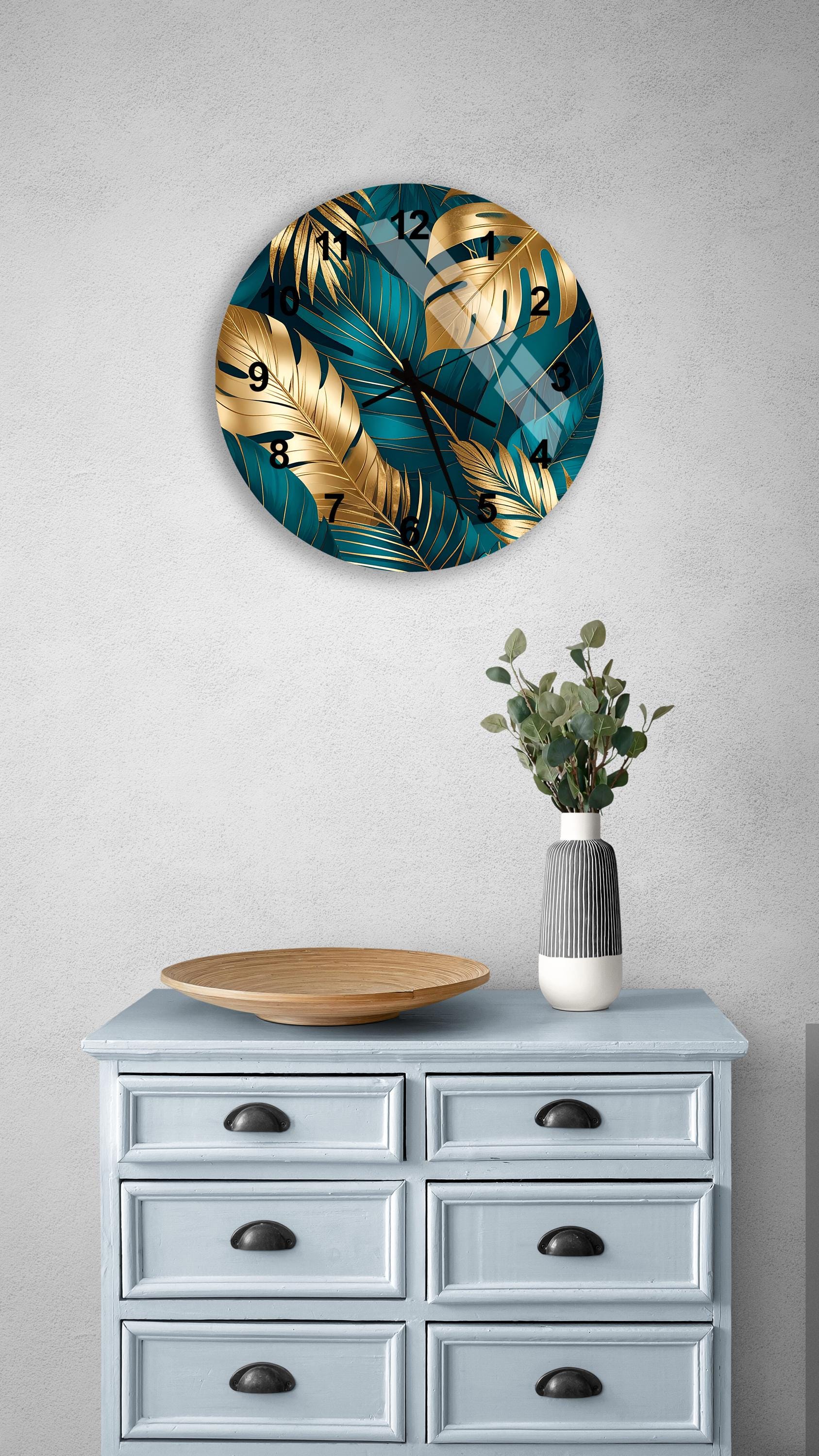 a wall clock with a tropical leaf design, a wooden bowl, and a vase with greenery, all placed on a light blue dresser with six drawers.