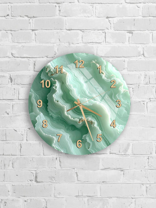 A round wall clock with a marble-like green and white design, mounted on a white brick wall.