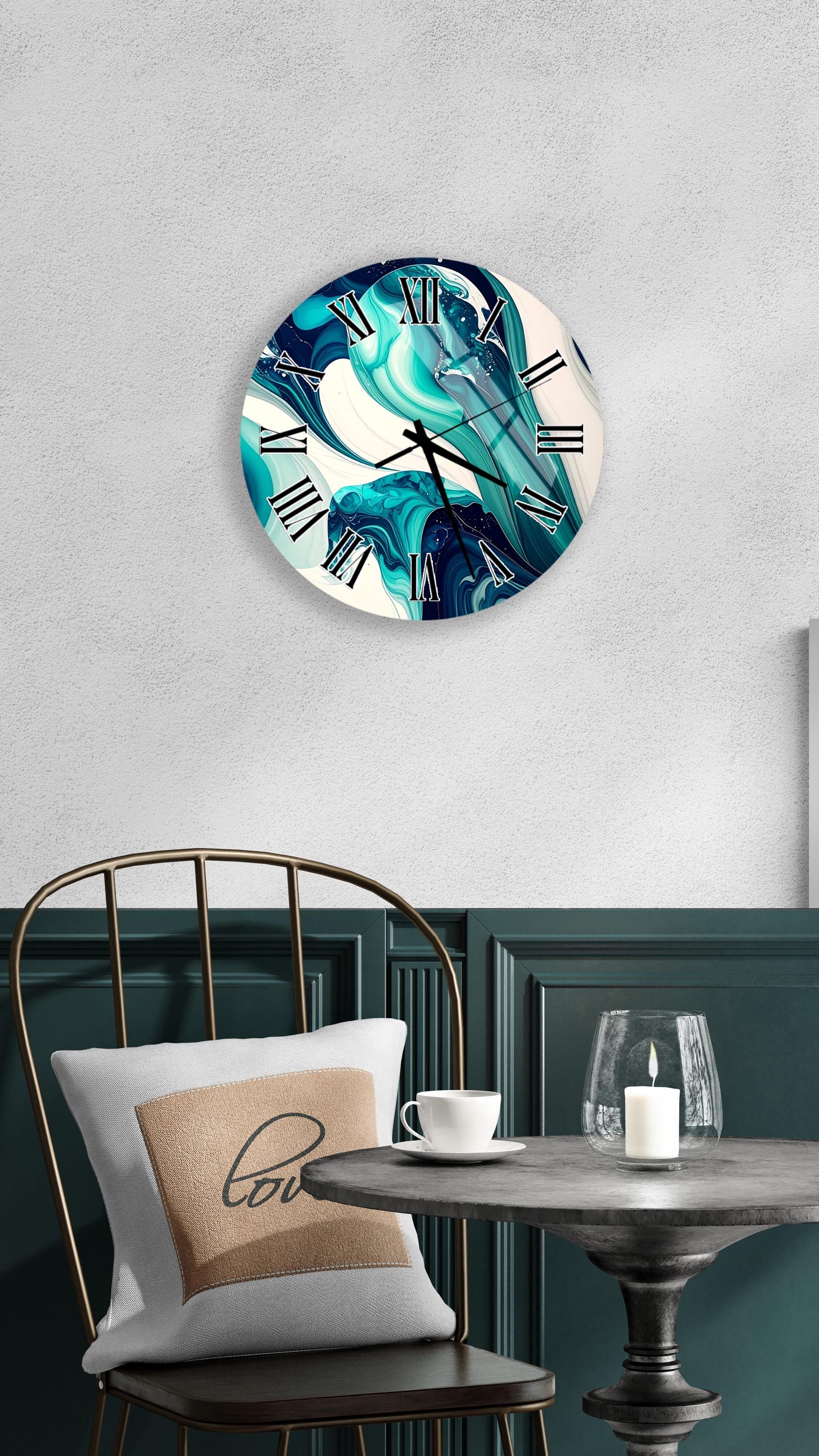 a modern interior design with a round wall clock displaying a blue and white abstract pattern, a white table with a candle and a glass, and a black metal chair with a white pillow.
