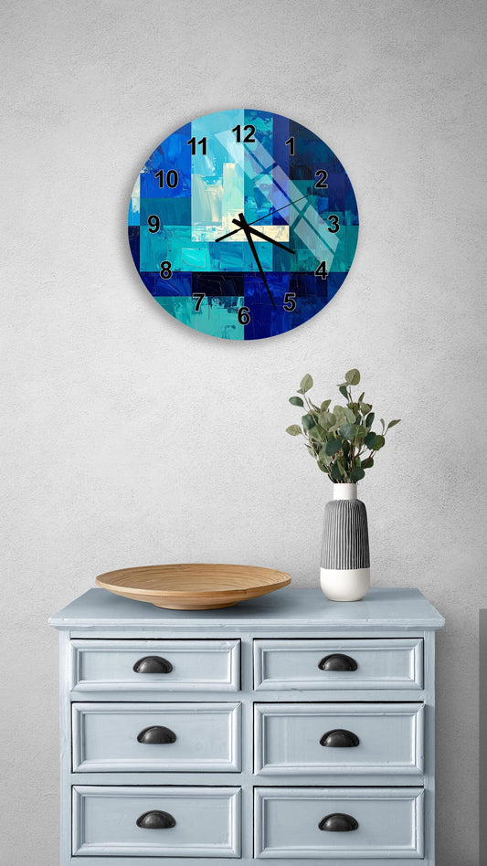 a blue and white clock with a geometric design, mounted on a wall above a light blue dresser with six drawers. The dresser also has a vase with greenery on it, and a wooden bowl on top.