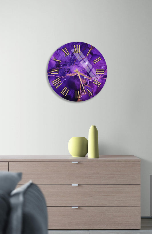 a purple clock with gold Roman numerals, mounted on a wall above a wooden dresser. The dresser has a vase and a small yellow pot on it.