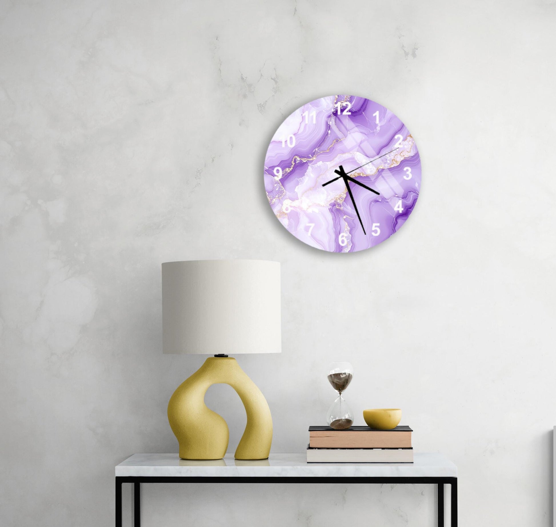a modern and minimalist interior design with a round clock featuring a purple marble pattern on the wall, a yellow lamp on a white table, and a stack of books and a glass of wine on the table.