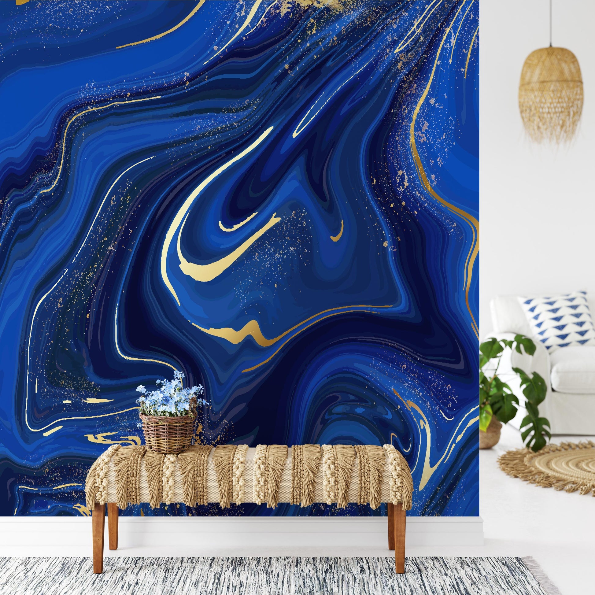 a living room with a large blue marble-style wall behind a bench with a woven blanket on it. The bench is positioned in front of a rug, and there is a potted plant nearby. The room also includes a white sofa and a hanging light fixture.