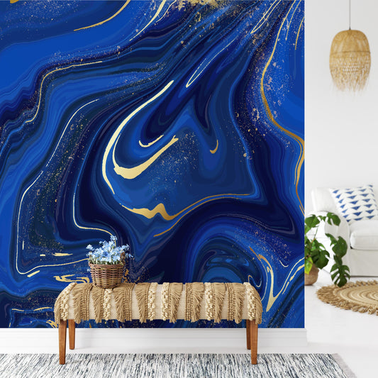 a living room with a large blue marble-style wall behind a bench with a woven blanket on it. The bench is positioned in front of a rug, and there is a potted plant nearby. The room also includes a white sofa and a hanging light fixture.