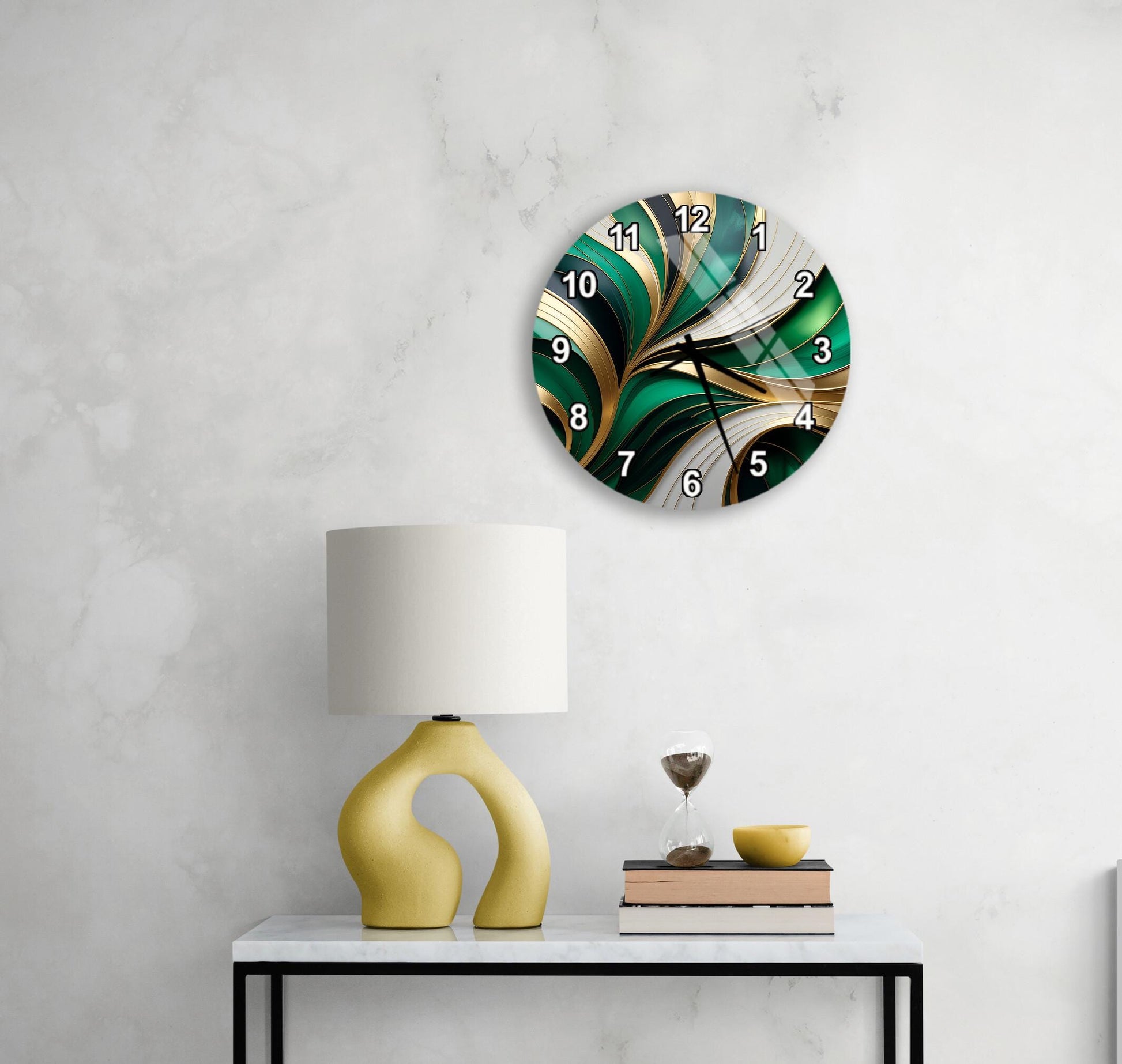 a modern, abstract clock with a green and gold design, mounted on a wall above a white table with a yellow lamp and a stack of books.