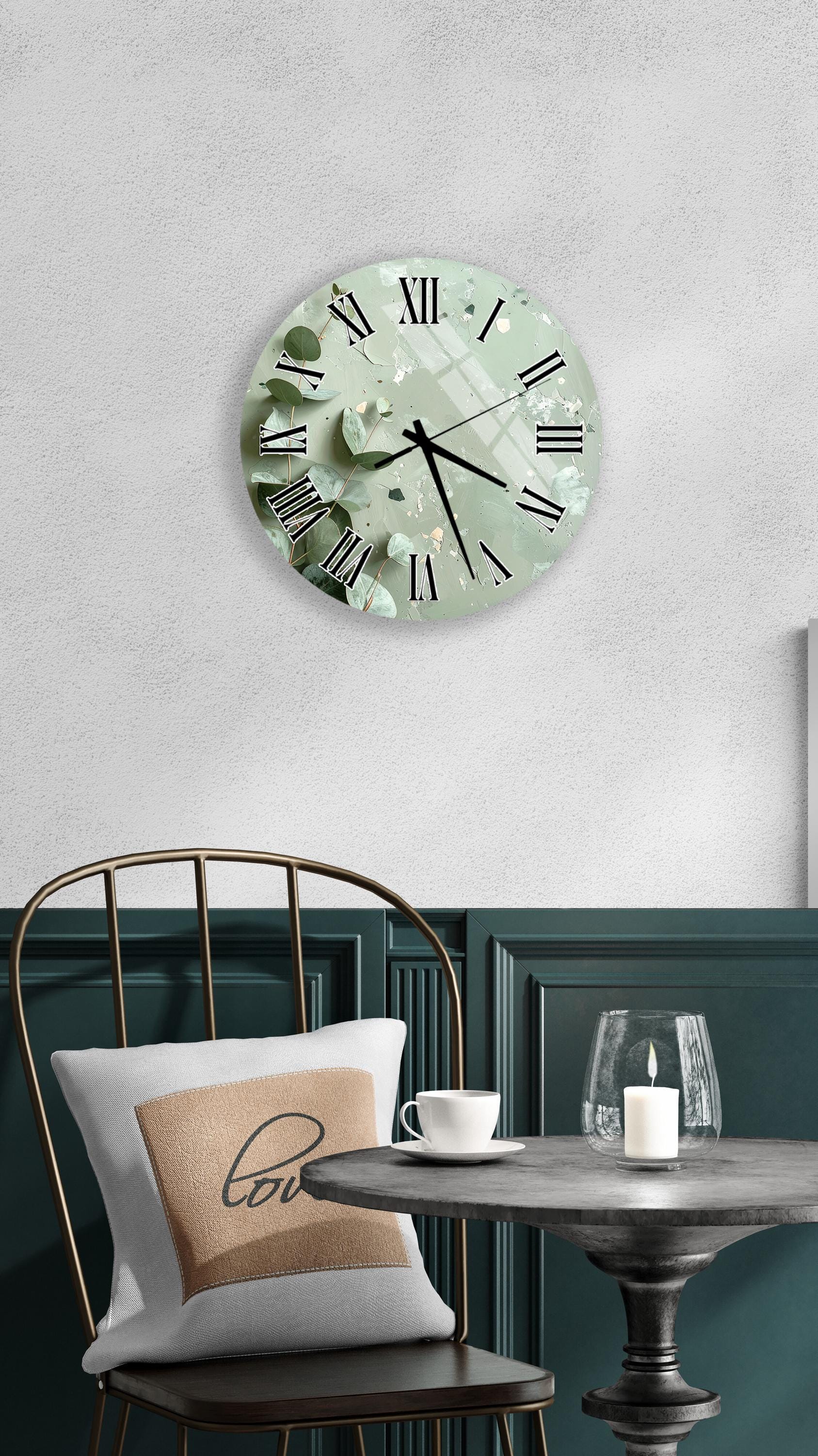 a wall clock with a green and white color scheme, a white table with a candle and a cup, and a black chair with a pillow.