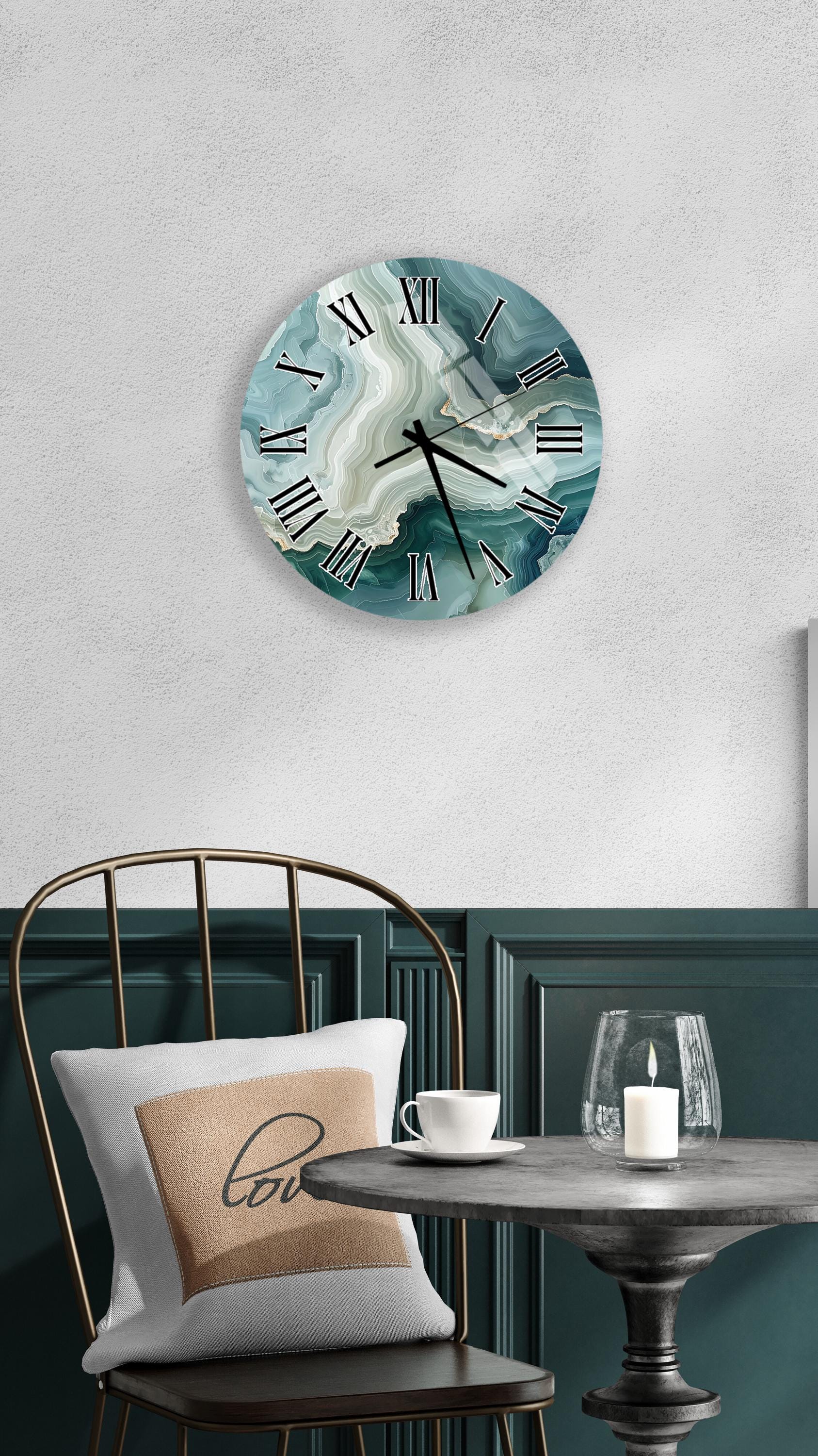 a wall clock with a marble-like design, a white table with a candle and a cup, and a chair with a pillow on it.