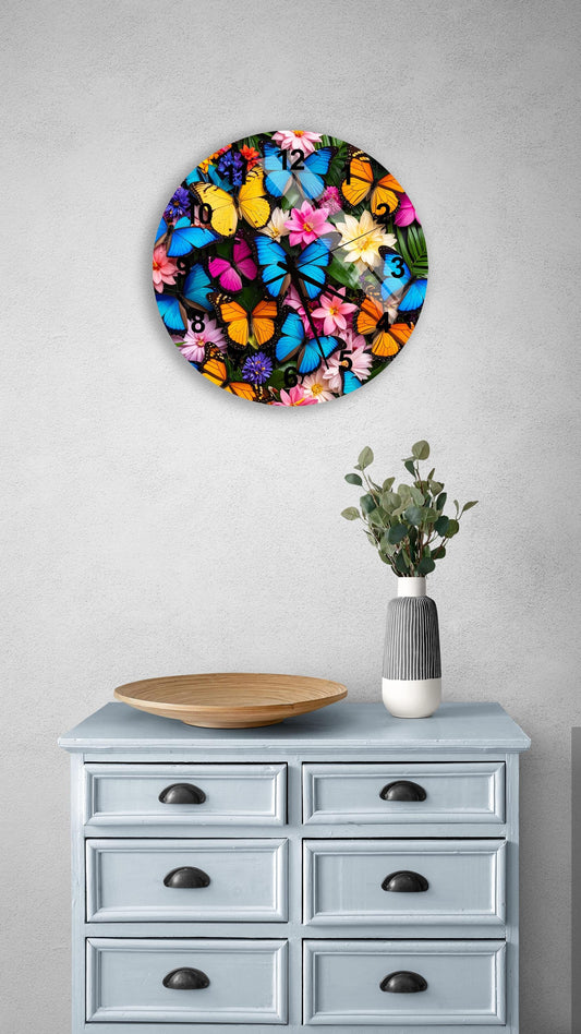 a round clock with a vibrant butterfly design on a white wall above a light blue dresser with six drawers. The dresser also has a wooden bowl and a vase with greenery on it.