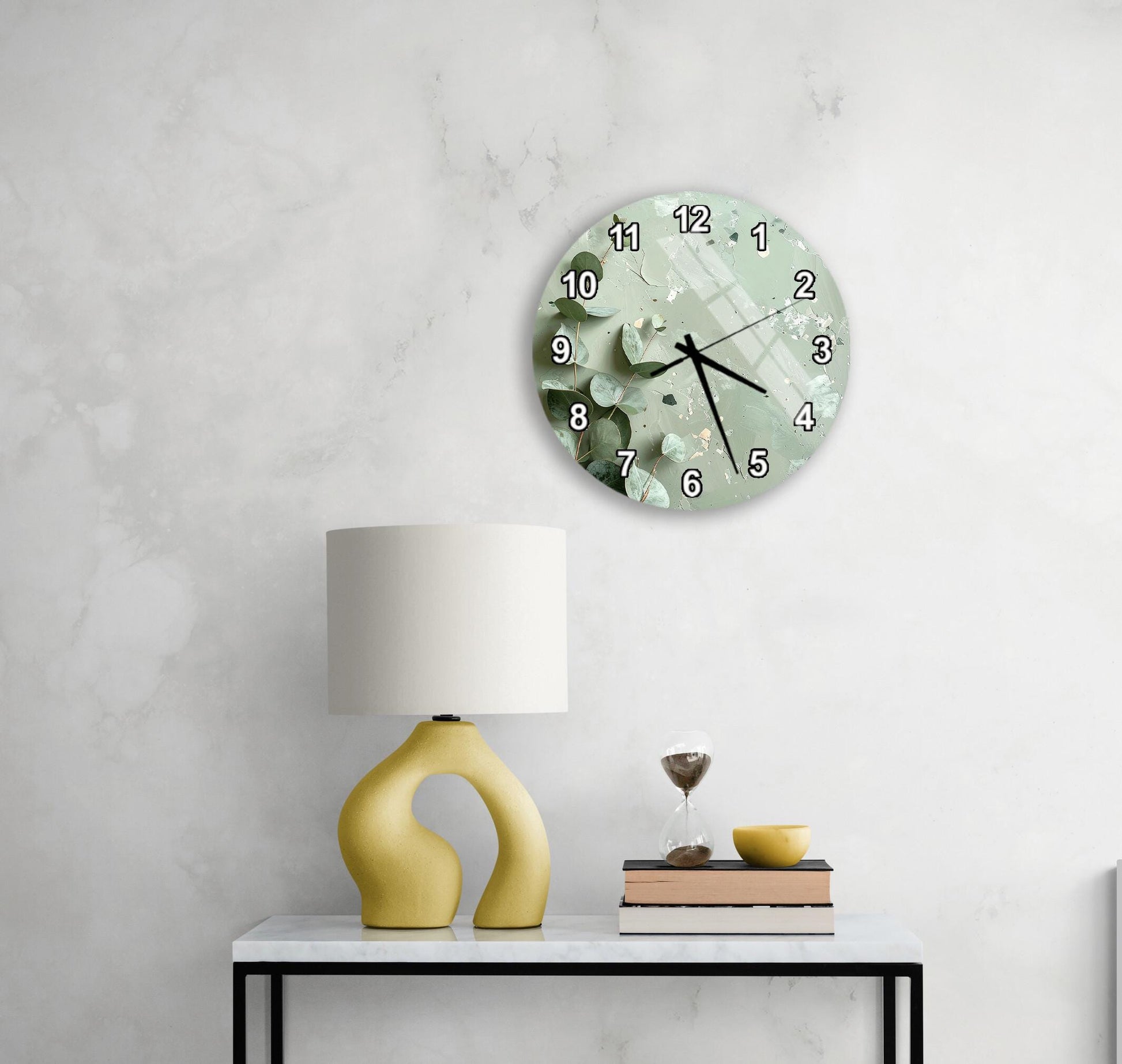 a modern, minimalist living space with a white wall, a round clock with a green and white design, a yellow lamp with a unique, curved base, and a small table with a book and a glass of water.