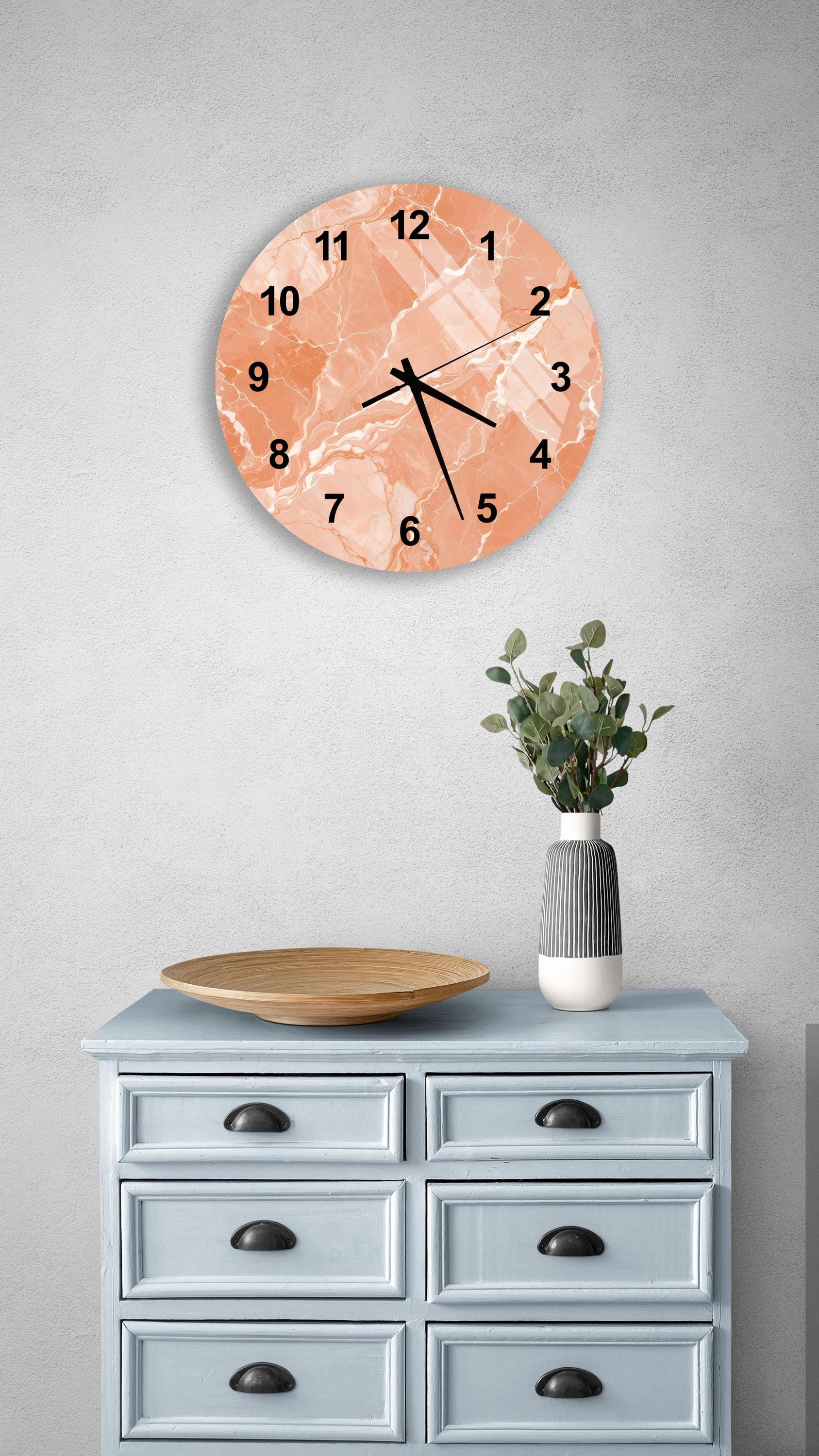 a light blue wooden dresser with a round clock hanging above it, a wooden plate on the dresser, and a vase with greenery on the dresser.