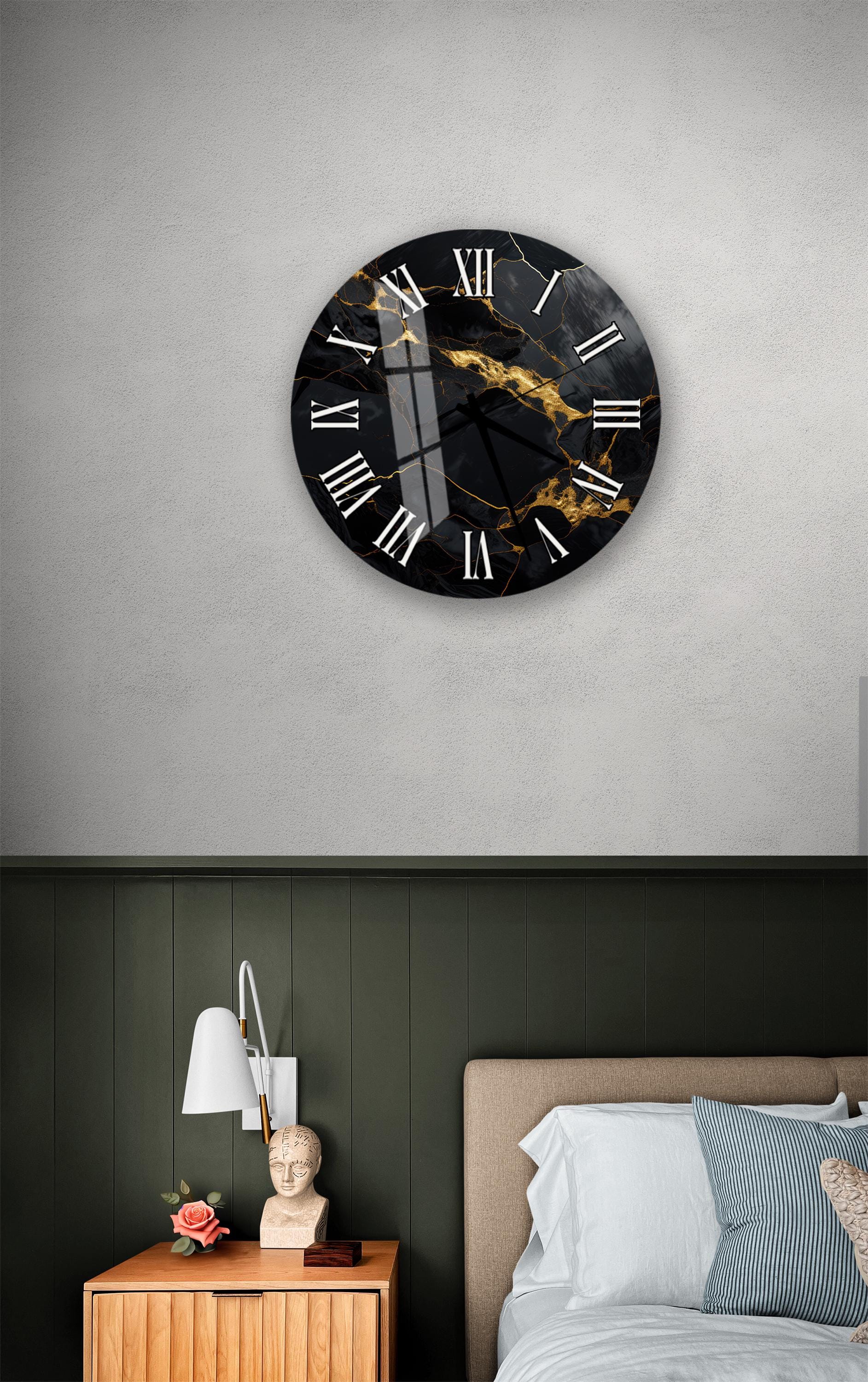 a bedroom setting with a large black and gold clock mounted on the wall above a bed. The clock has a marble-like design and is positioned at eye level. The room has a green wall, a wooden nightstand with a lamp, and a bed with white sheets.