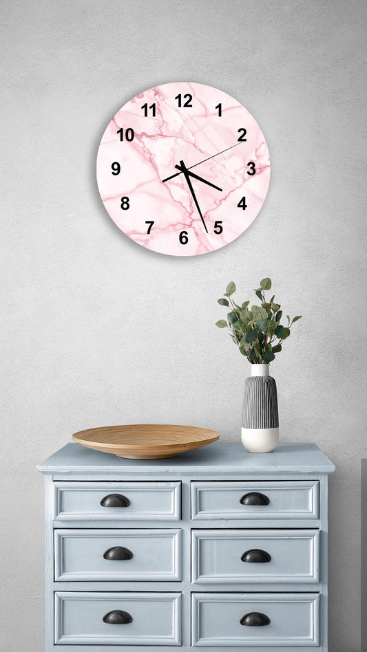 a wall clock with a pink marble design, mounted on a wall above a light blue dresser with six drawers. The dresser also has a wooden tray and a vase with greenery on it.