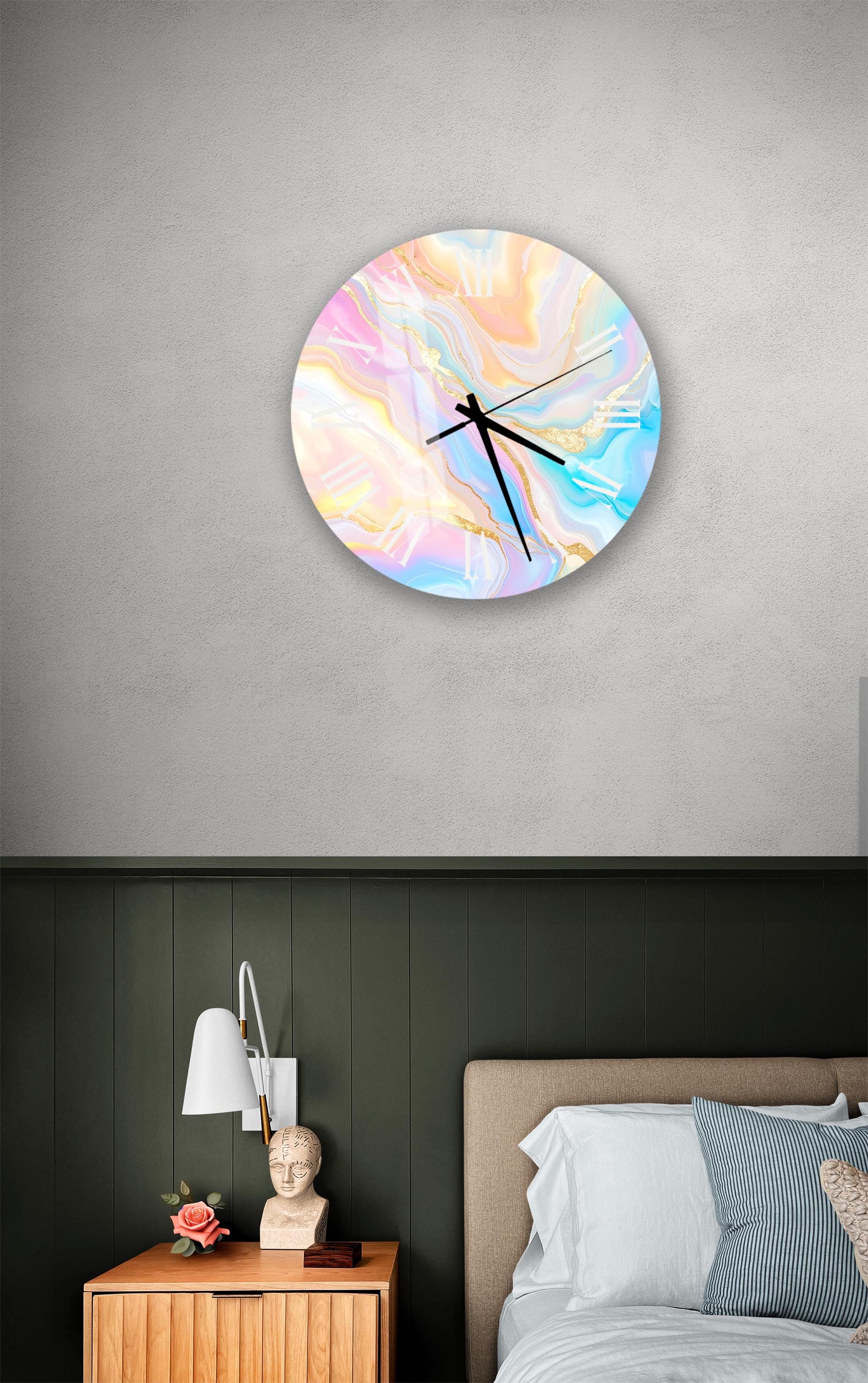 a bedroom setting with a round wall clock displaying a colorful abstract design, a wooden nightstand with a lamp, and a bed with white sheets and a blue and white striped pillow.