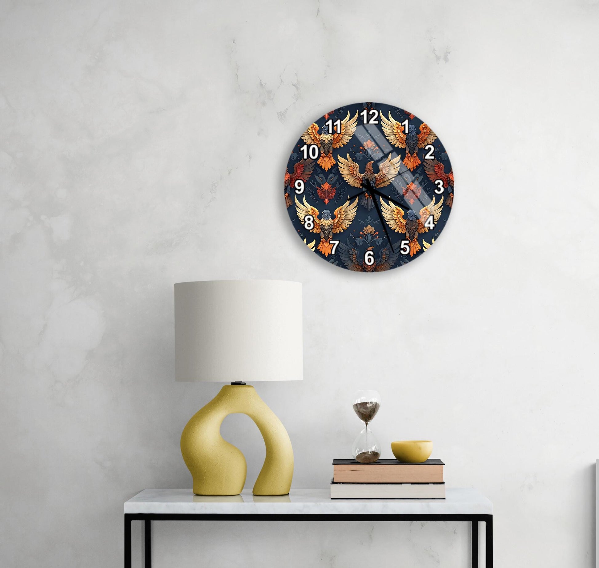 a wall clock with a bird design, a yellow lamp, a stack of books, and a glass of wine on a white table.