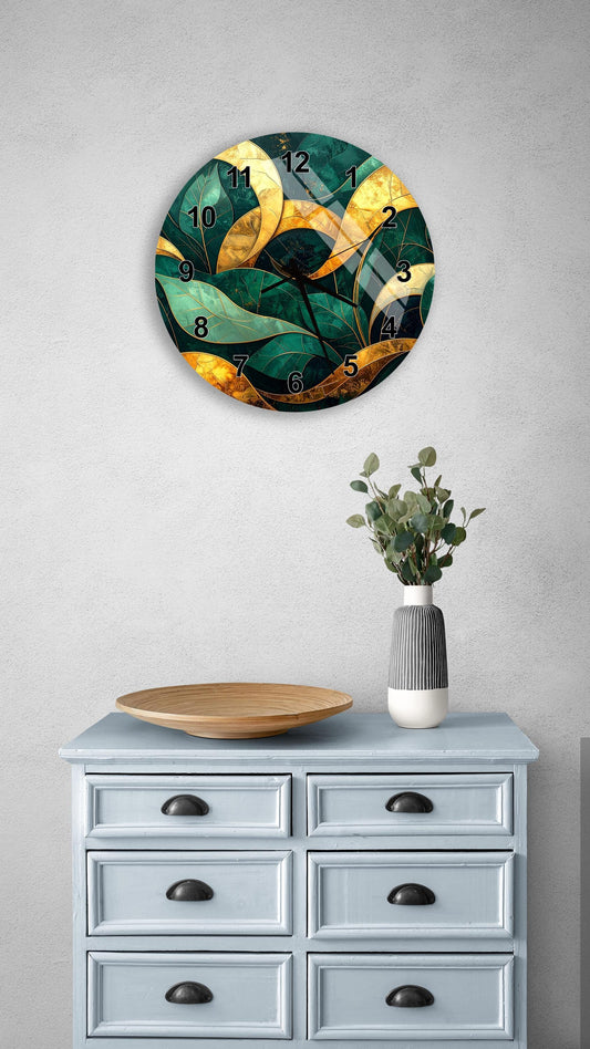 a wall clock with a green and gold leafy design, mounted on a wall above a light blue dresser with six drawers. The dresser also has a wooden plate and a vase with greenery on it.