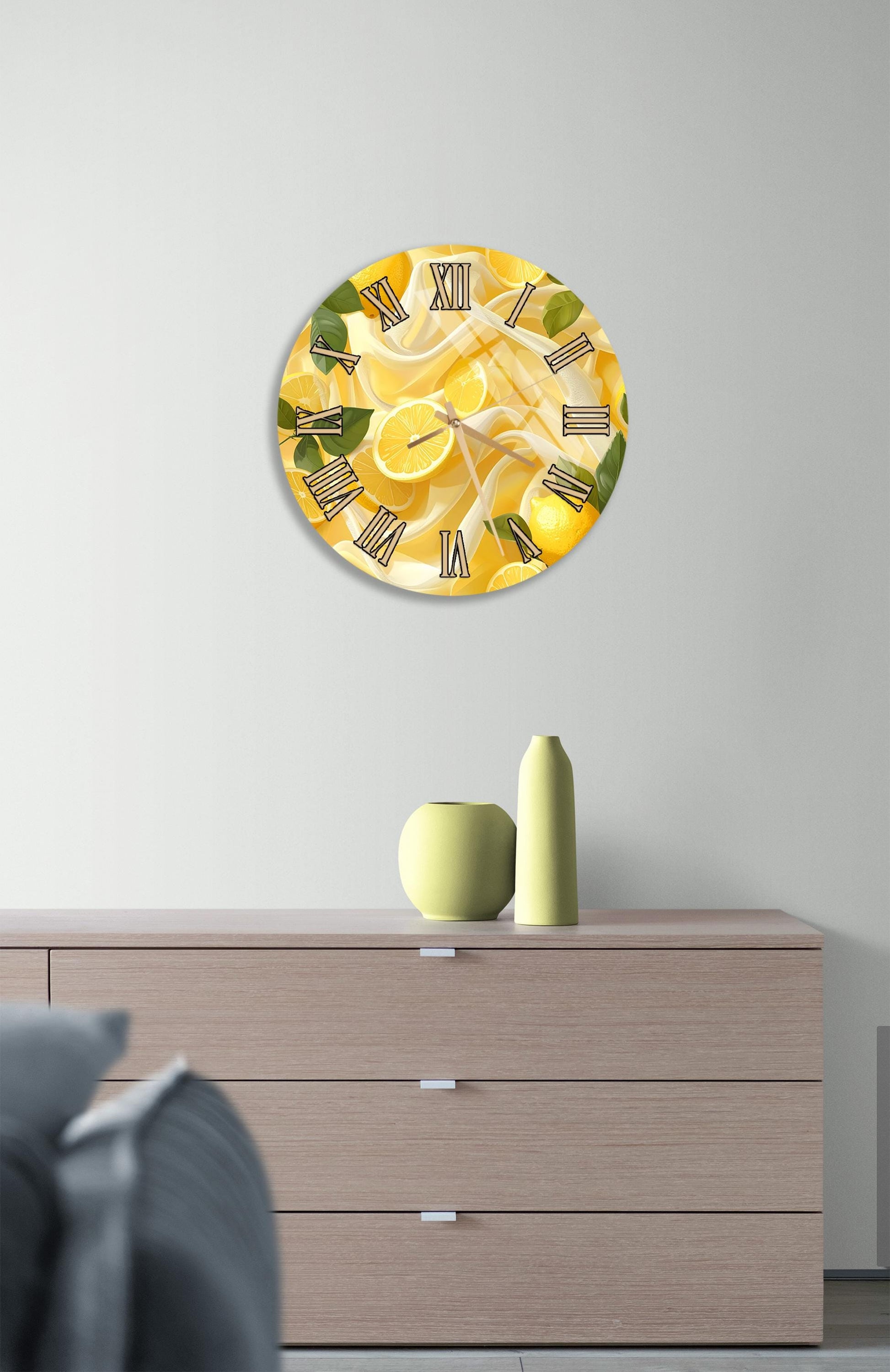 a wall clock with a lemon design, mounted on a wall above a wooden dresser with a vase and a small sculpture on top.