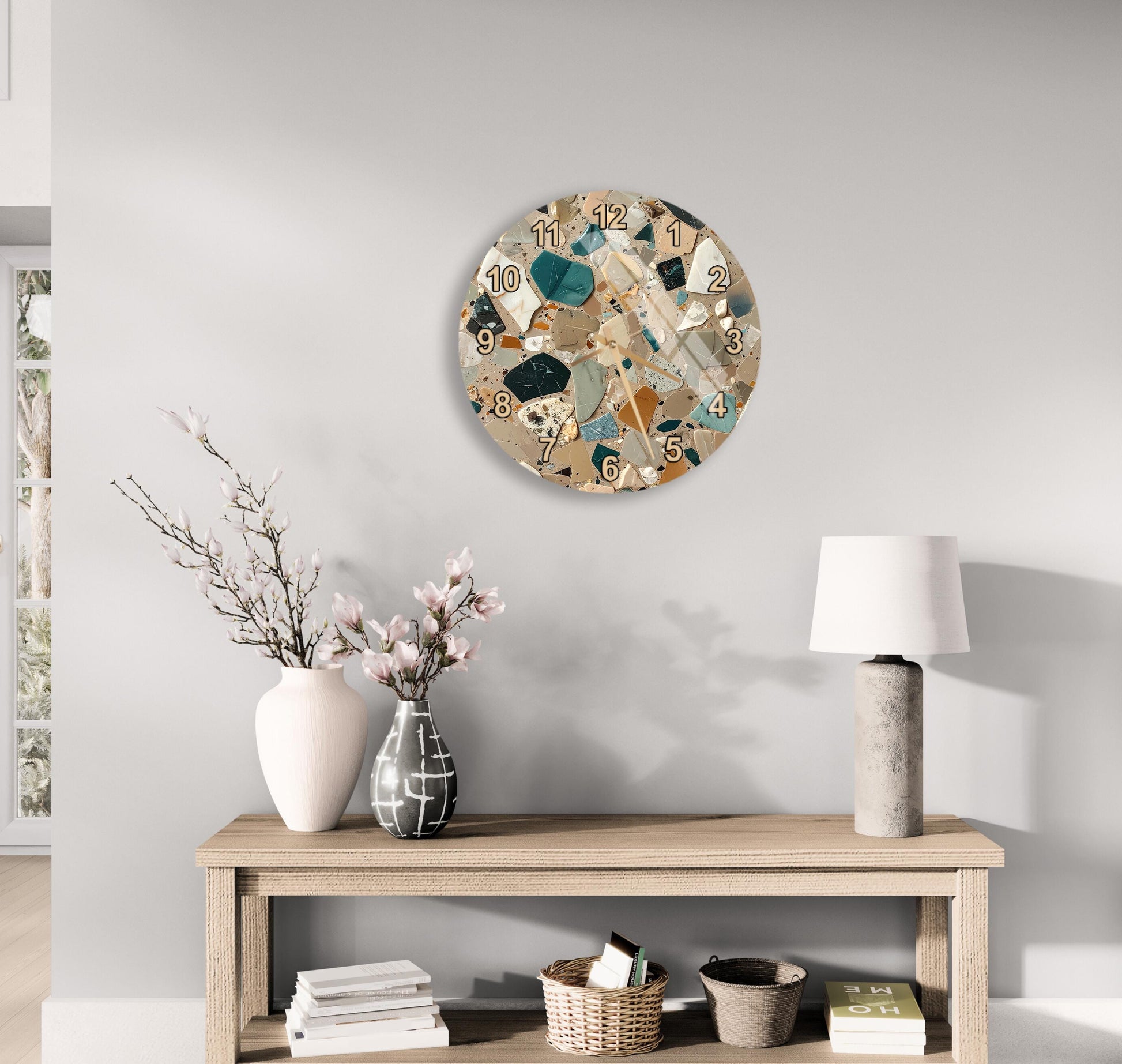 a wooden table with a lamp, a vase with flowers, and a clock on the wall above it.