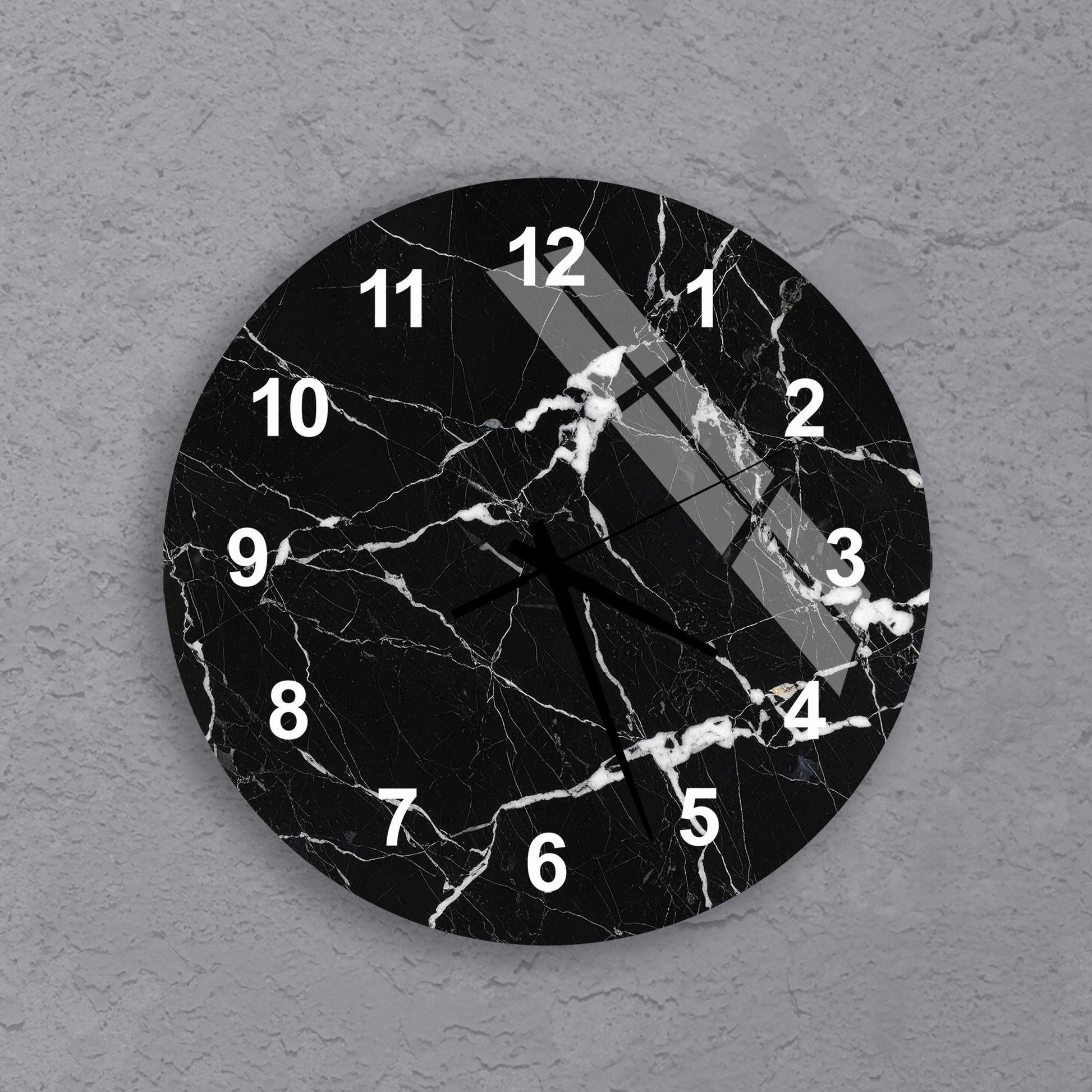 A black and white clock with a marble-like texture and white numbers on a gray background.