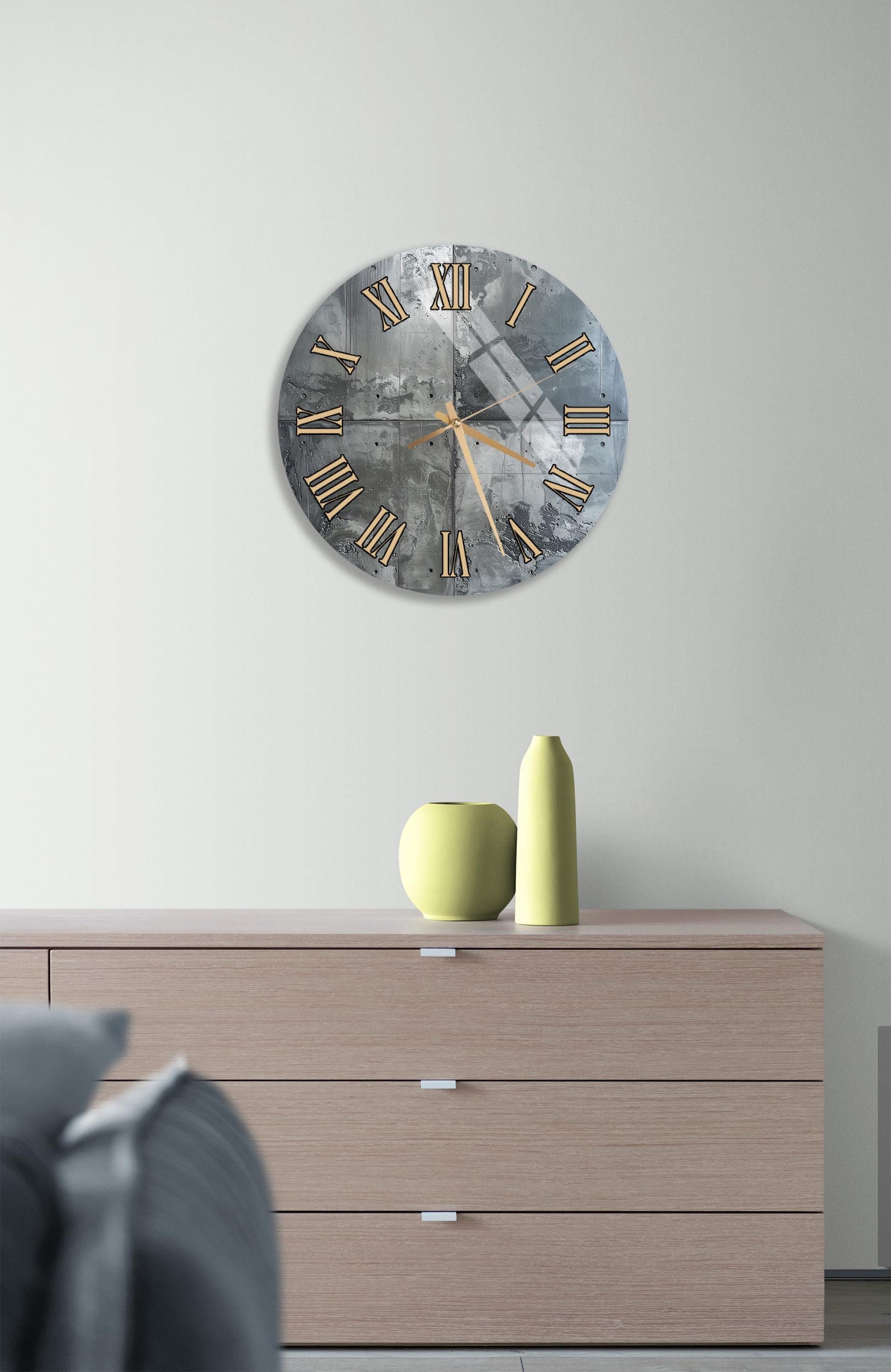 a modern living room with a large wall clock displaying Roman numerals, a wooden dresser with a vase and a small sculpture, and a gray couch in the background.