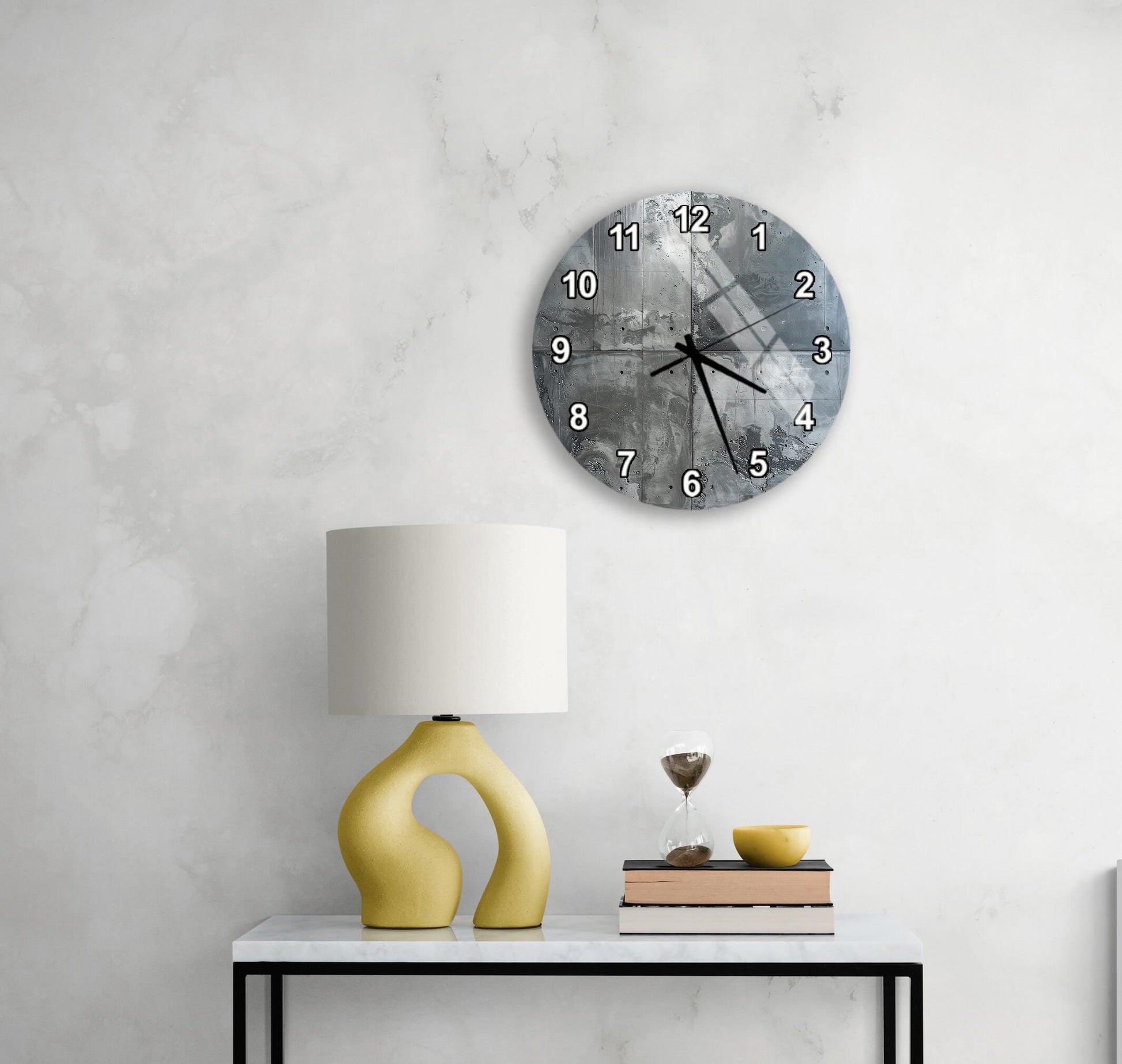 a modern living room with a white marble wall, a round clock with a black and white design, a yellow lamp with a unique curved base, and a small table with a stack of books and a glass of wine.