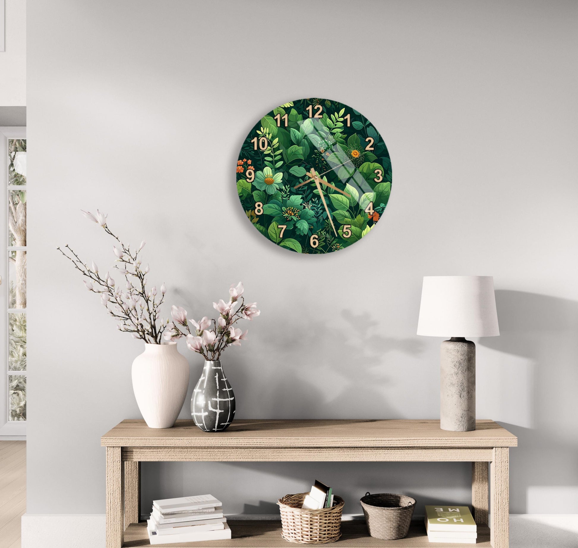 a clock with a green and white floral design hanging on a wall above a wooden table with various decorative items, including a vase with flowers, a lamp, and a stack of books.