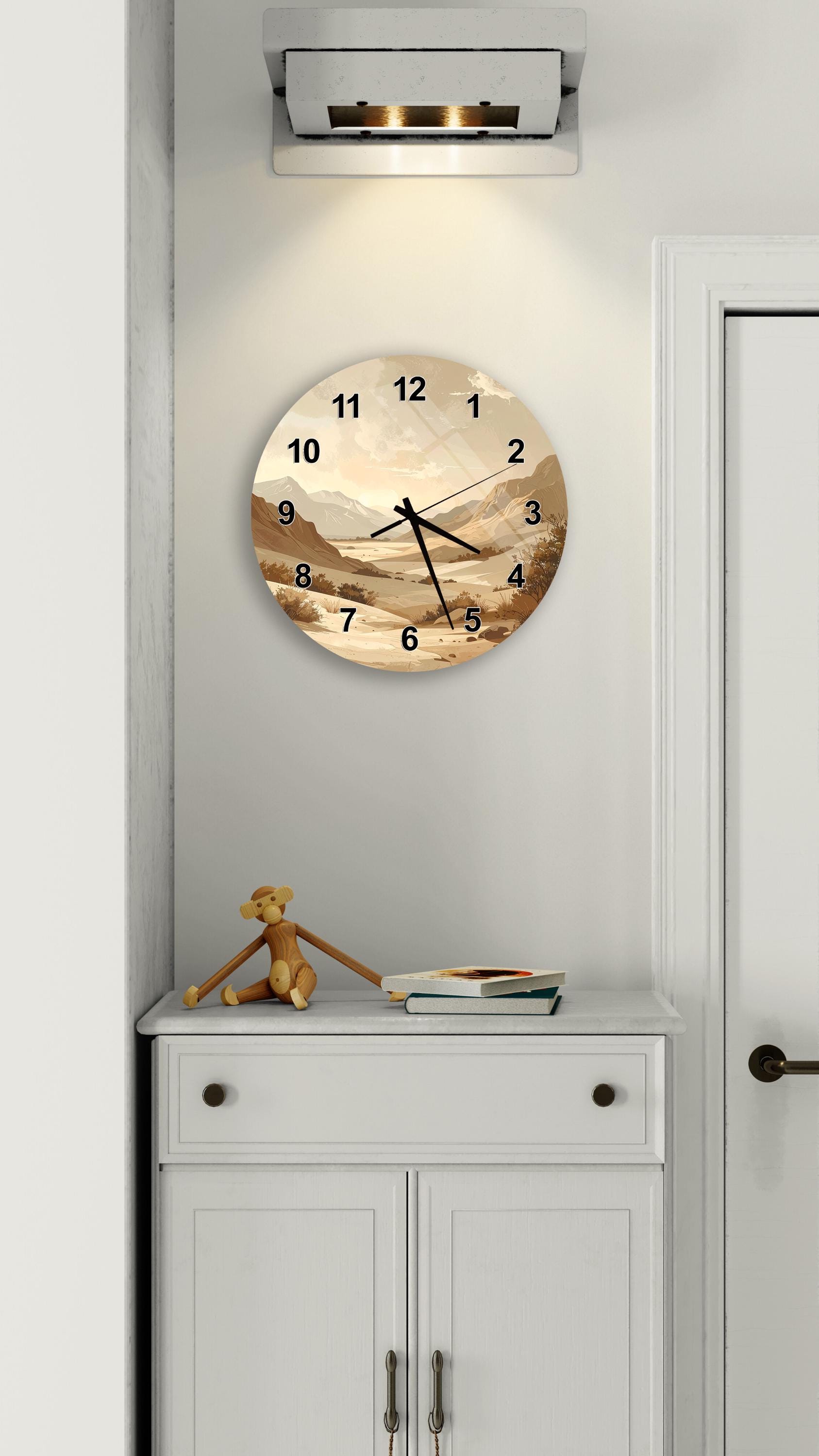 a wall clock with a landscape scene on its face, mounted on a white wall above a white cabinet.