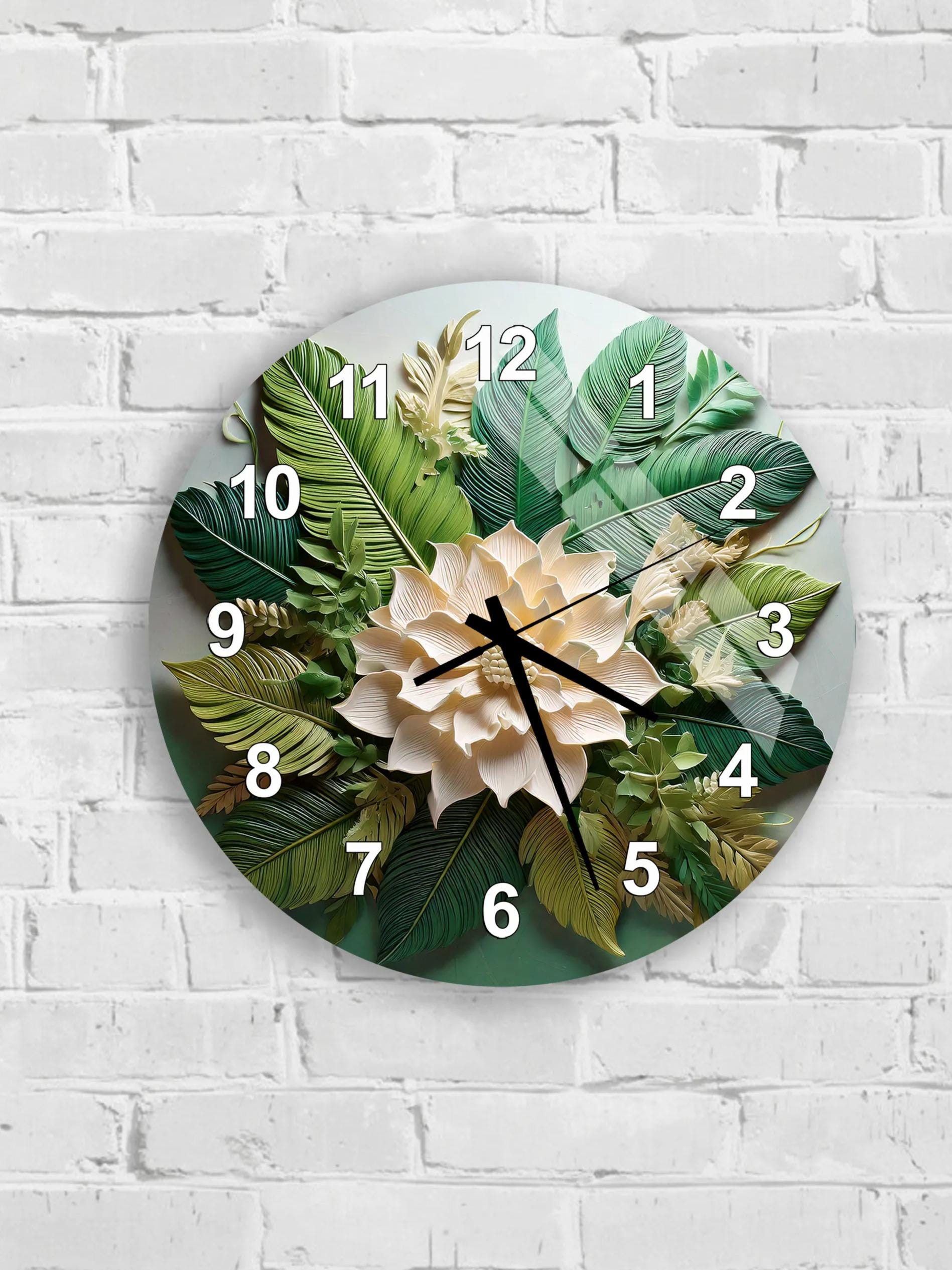 A wall clock with a floral design featuring green leaves and a white flower.