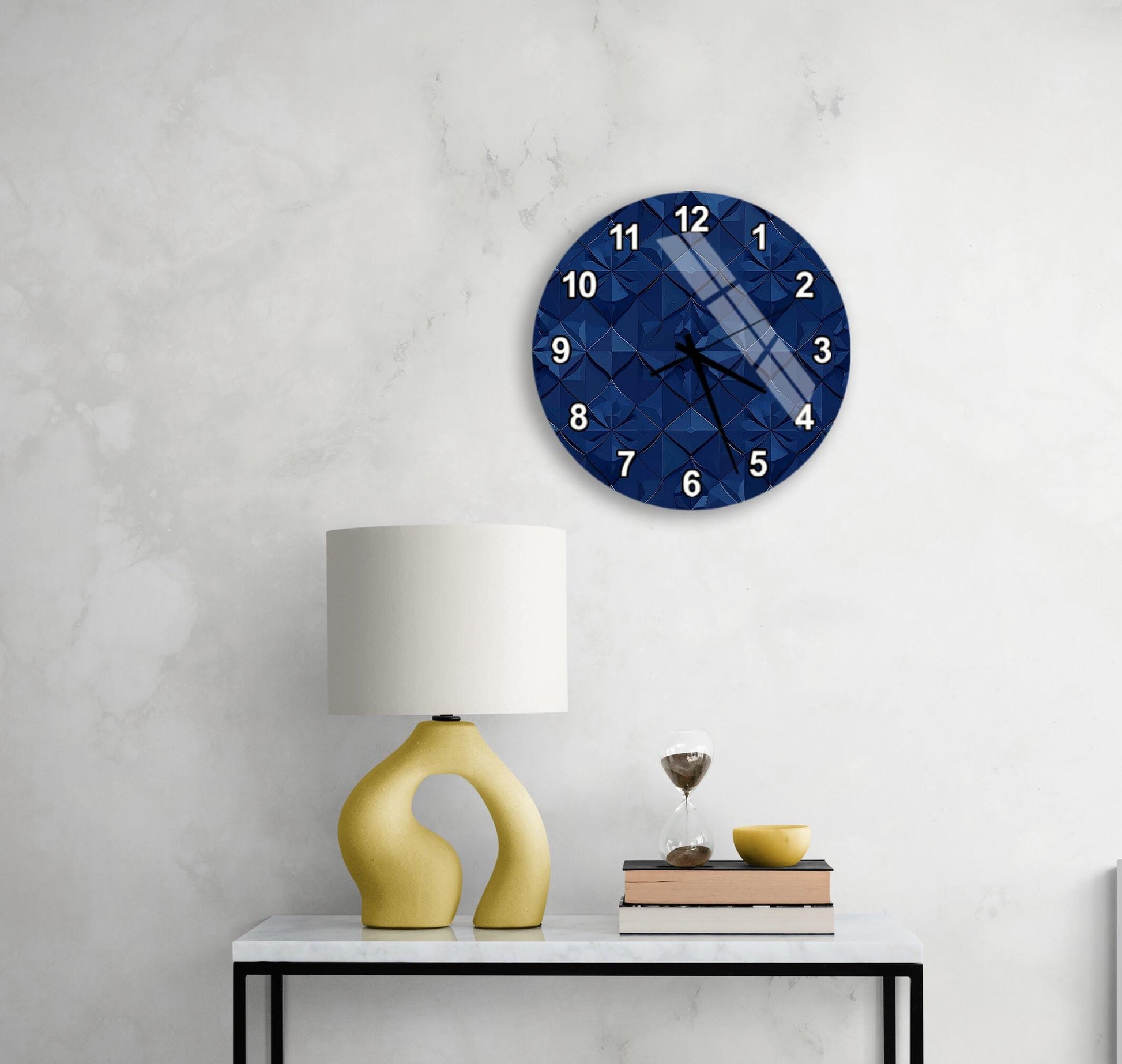 a modern living room with a white marble wall, a round blue clock with a geometric pattern, a yellow lamp with a unique curved base, a stack of books, and a glass of wine on a white table.