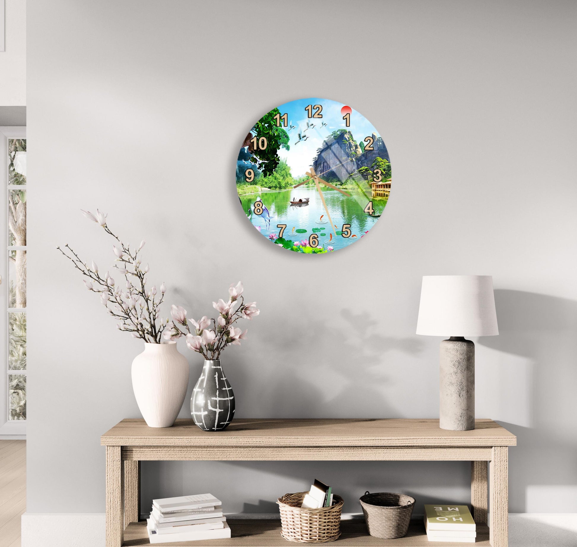 a wall clock with a scenic outdoor view, a wooden table with a lamp, a vase with flowers, and some books on a shelf.