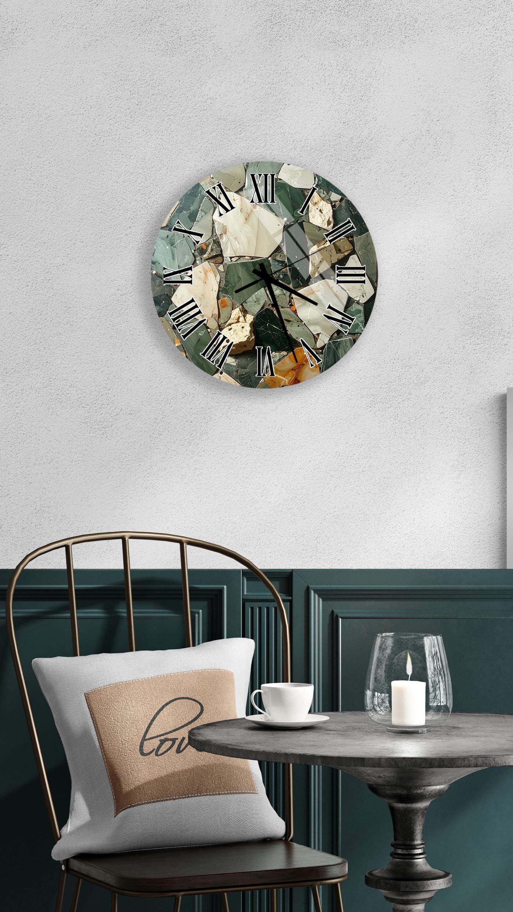 a wall clock with a unique, mosaic-like design, mounted on a wall above a dining table with a white tablecloth. The table is set with a white cup and a candle, creating a cozy and inviting atmosphere.